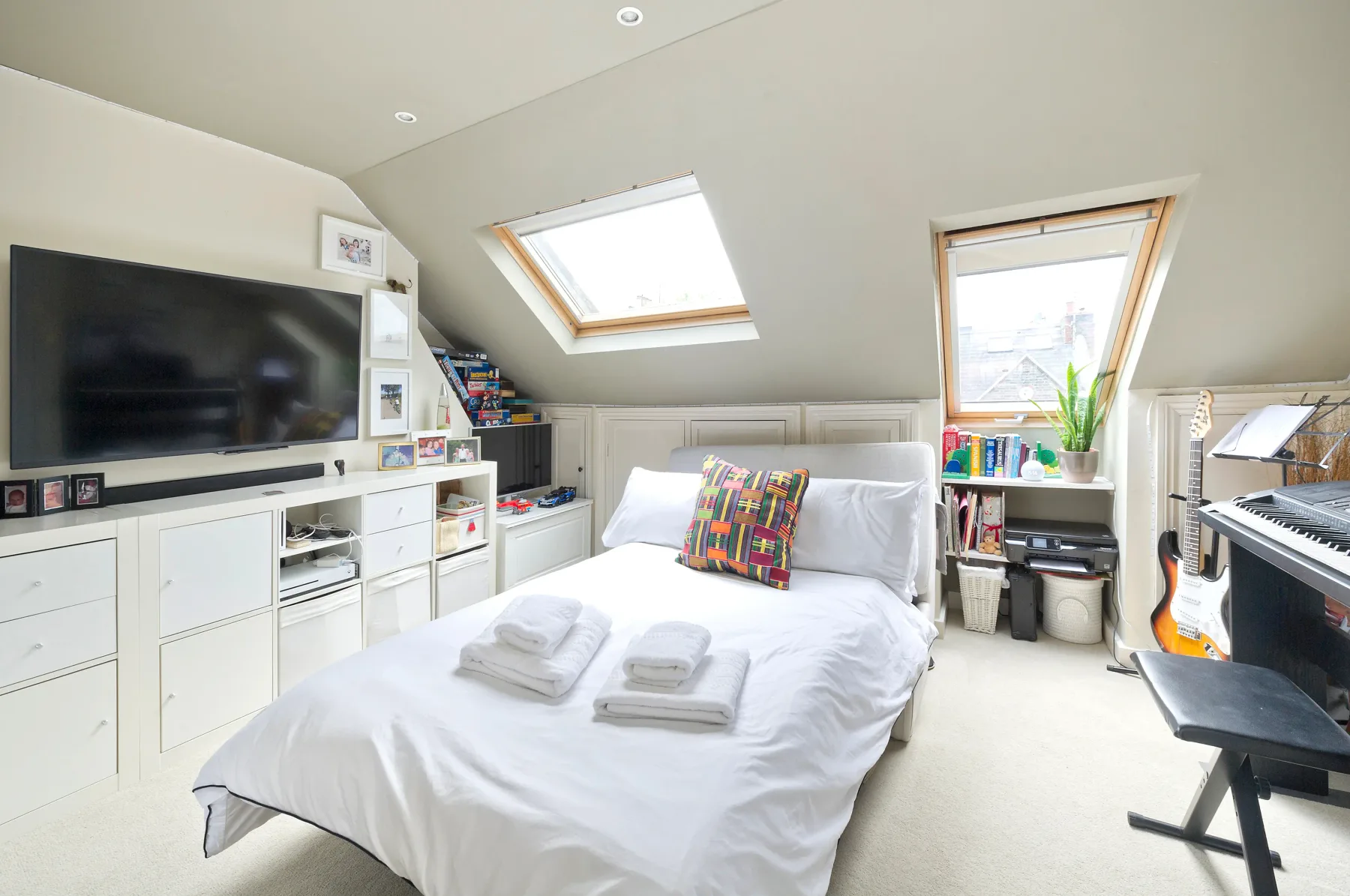 A bright attic bedroom with a bed, built-in storage, and sloped ceilings.