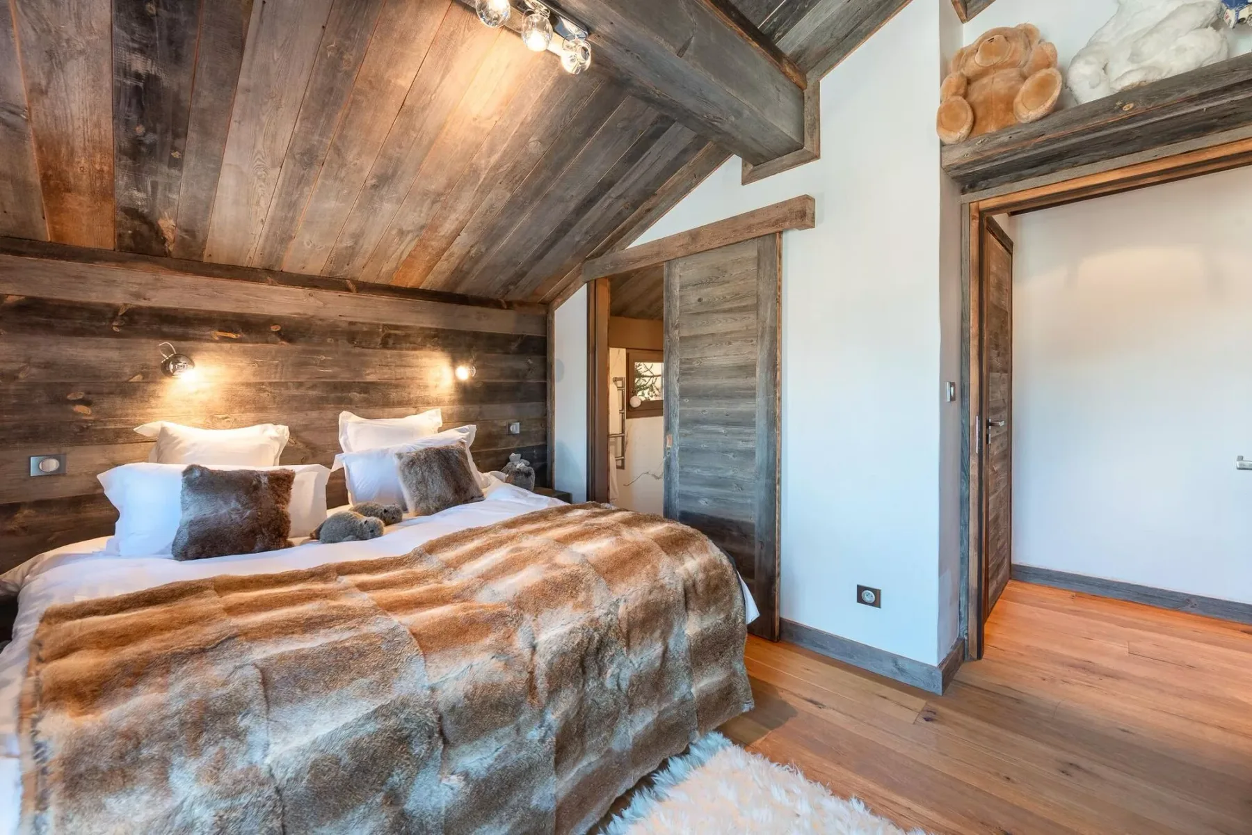 Un dormitorio con una cama bajo un techo de madera inclinado.