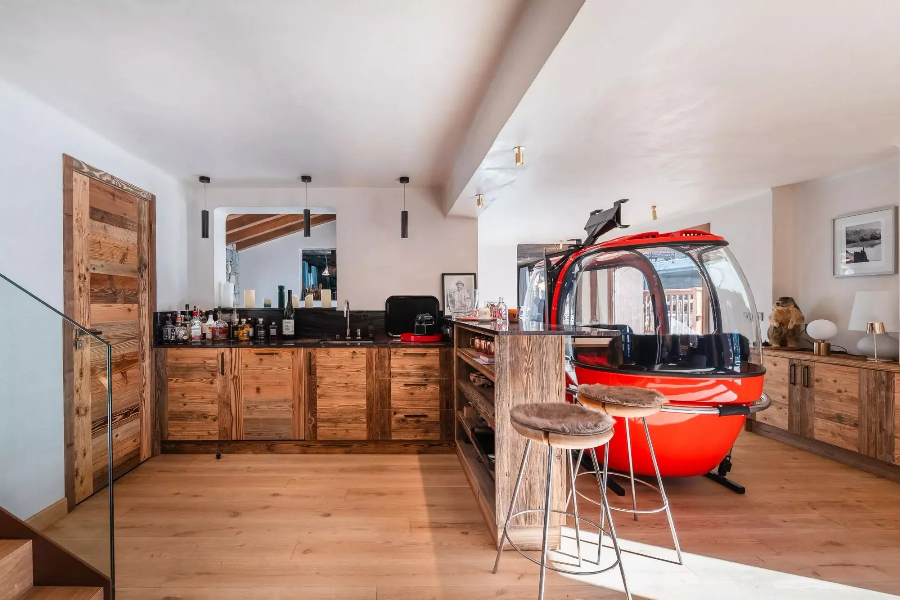 Una cocina con paneles de madera y una cabina roja de teleférico en exhibición.