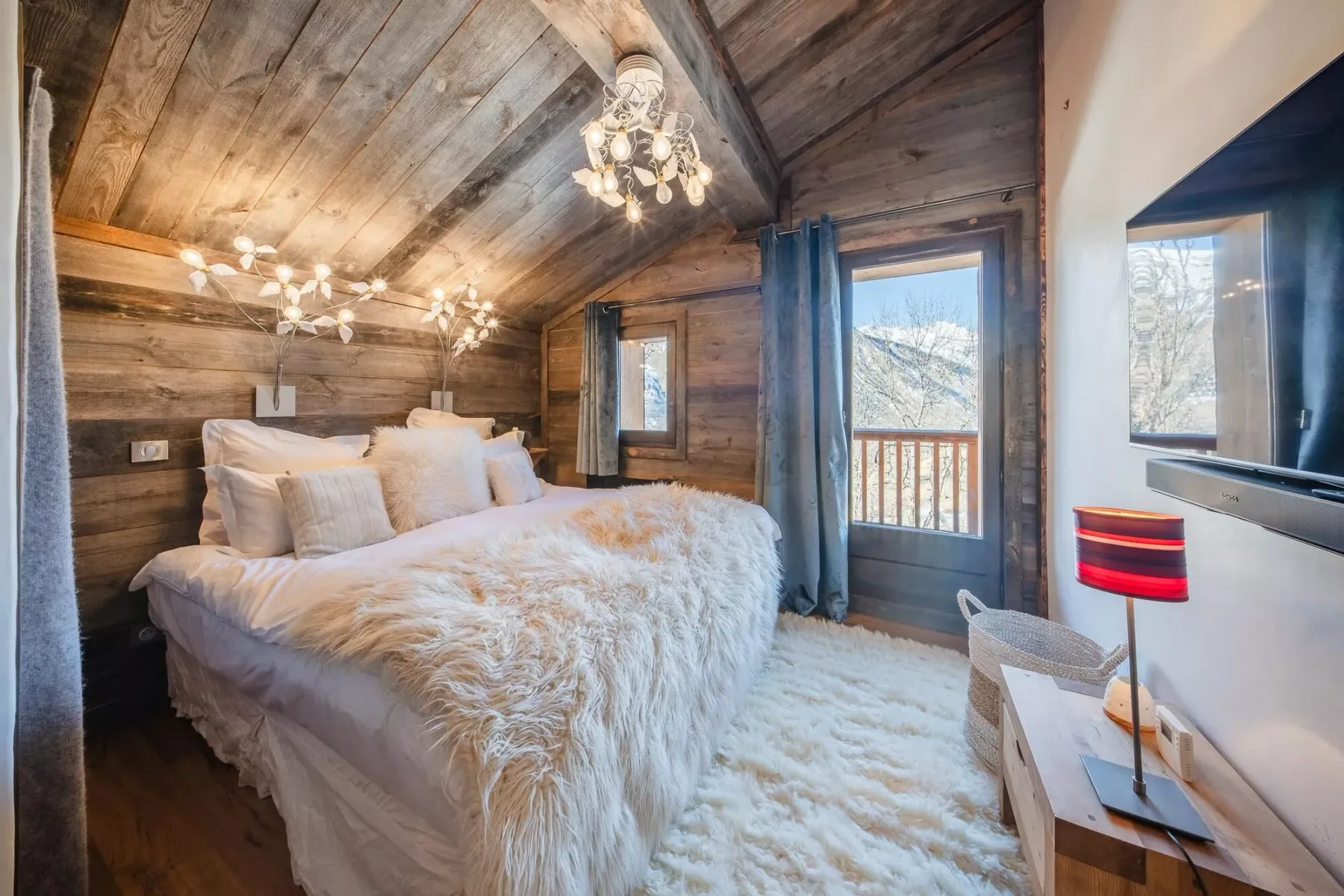 Un dormitorio con una cama, paredes revestidas de madera y una puerta al balcón.