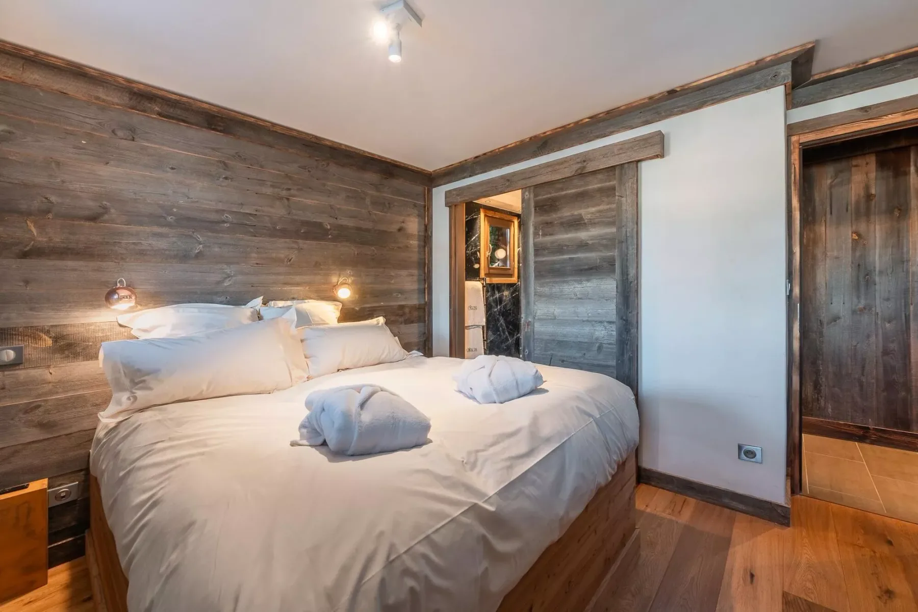 Un dormitorio con una cama grande y paredes revestidas de madera rústica.