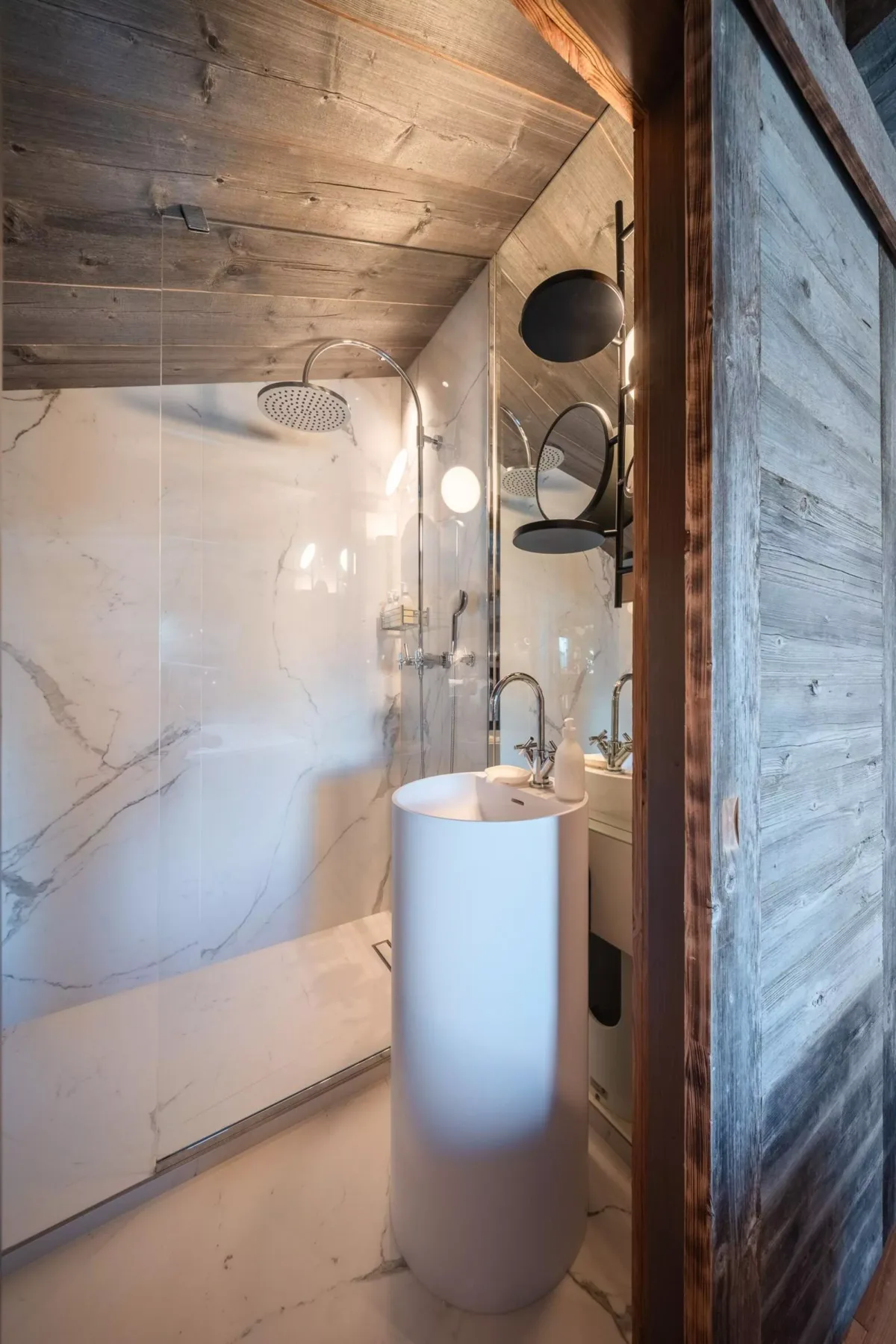 Un baño de mármol con ducha a ras de suelo y lavabo independiente.