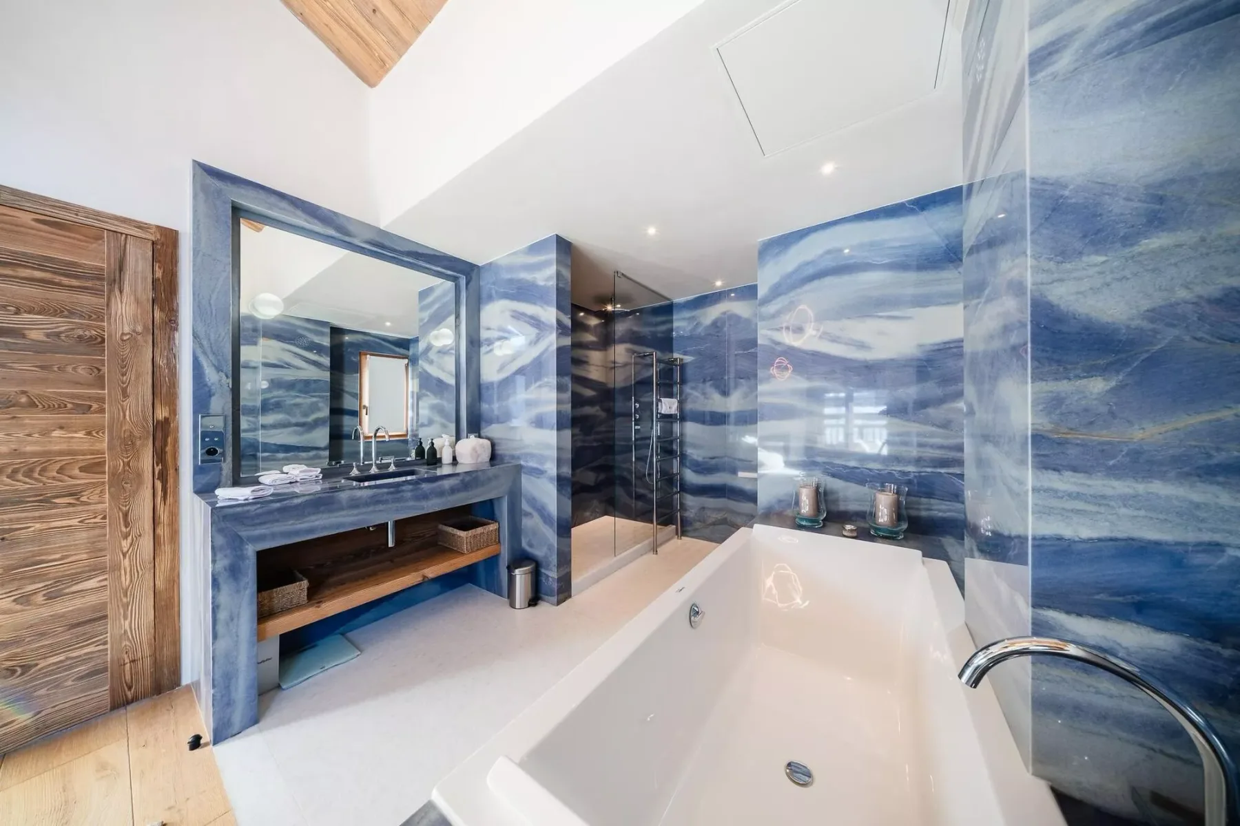 Un baño con bañera, ducha de vidrio y paredes con diseño azul.