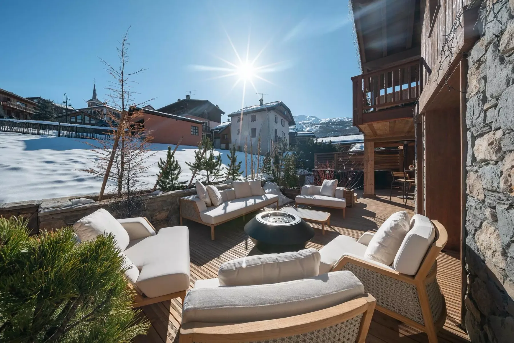 Una zona exterior de asientos al sol con sillones acolchados y una mesa baja redonda.