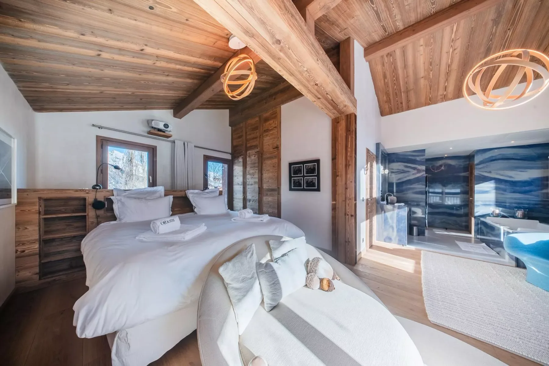 Un dormitorio con una cama grande y un baño contiguo con una pared en tonos azules.