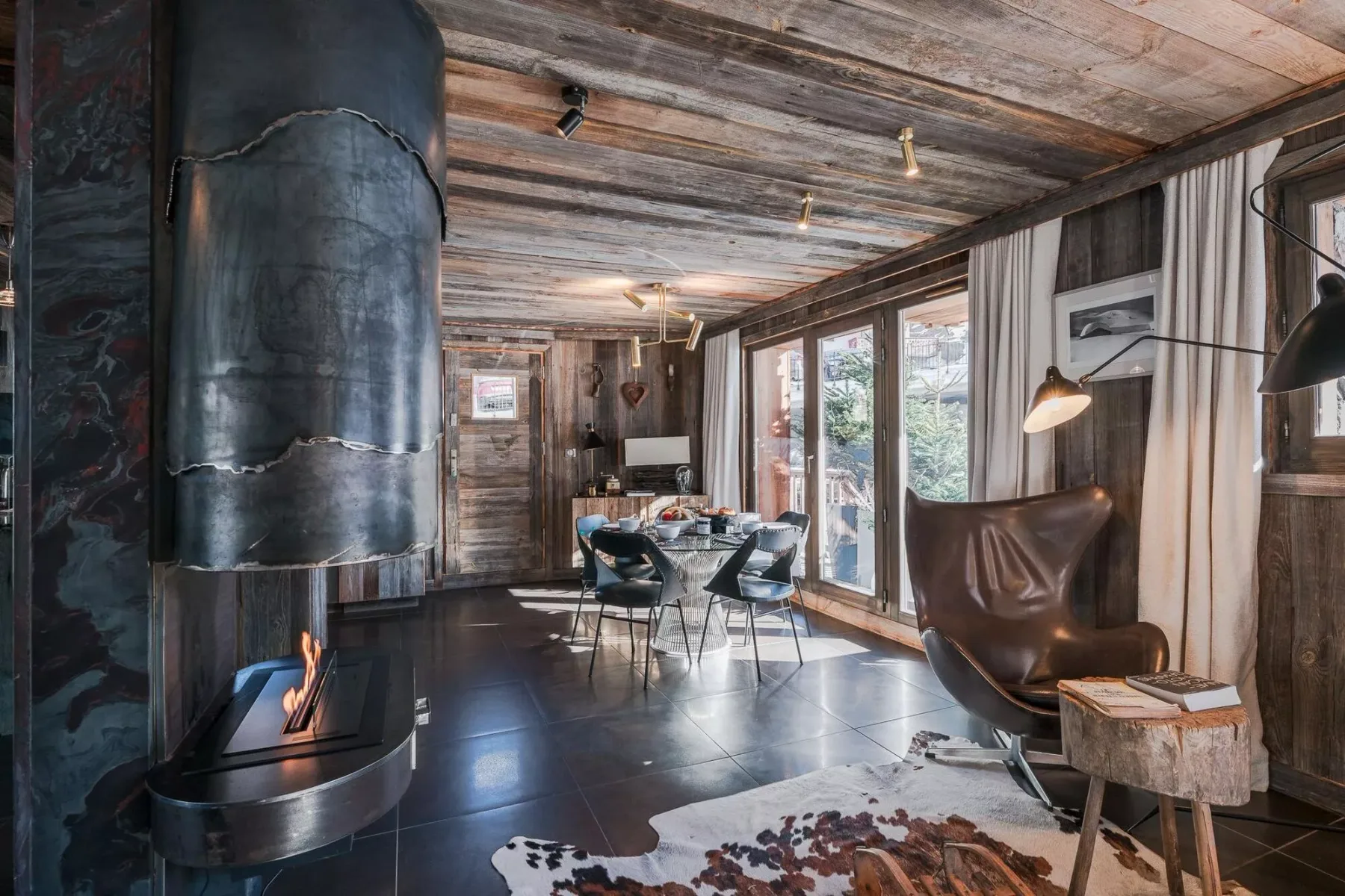 Una sala rústica con comedor, mesa, asientos y chimenea.