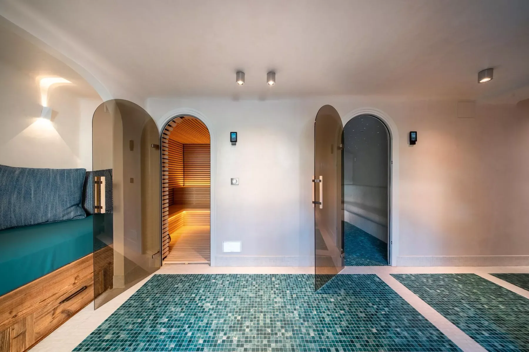 Un pasillo interior con azulejos, puertas arqueadas y una zona de asientos integrada.
