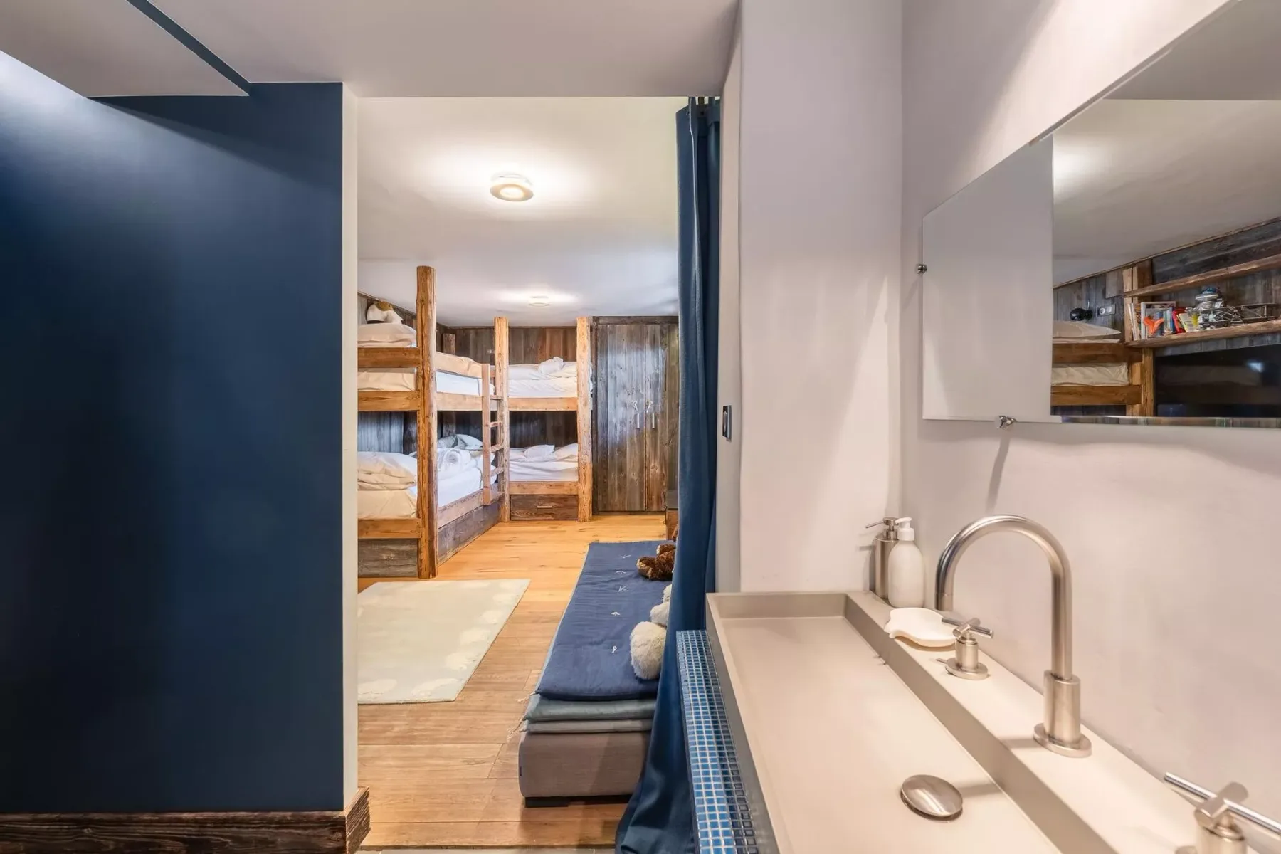 Una zona para dormir con literas de madera y un lavabo en primer plano.