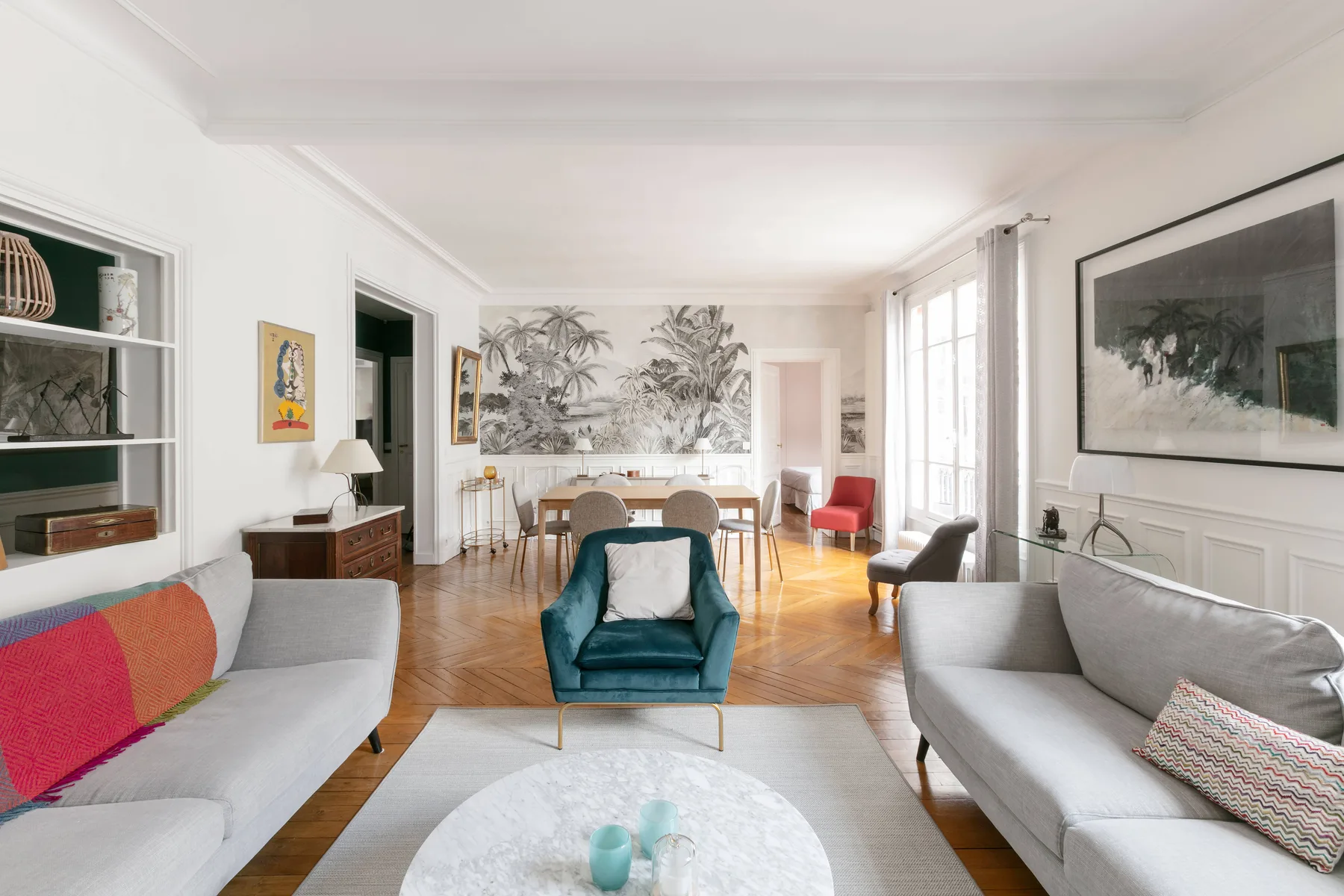 Una sala de estar luminosa con sofás, un sillón y una mesa de comedor.