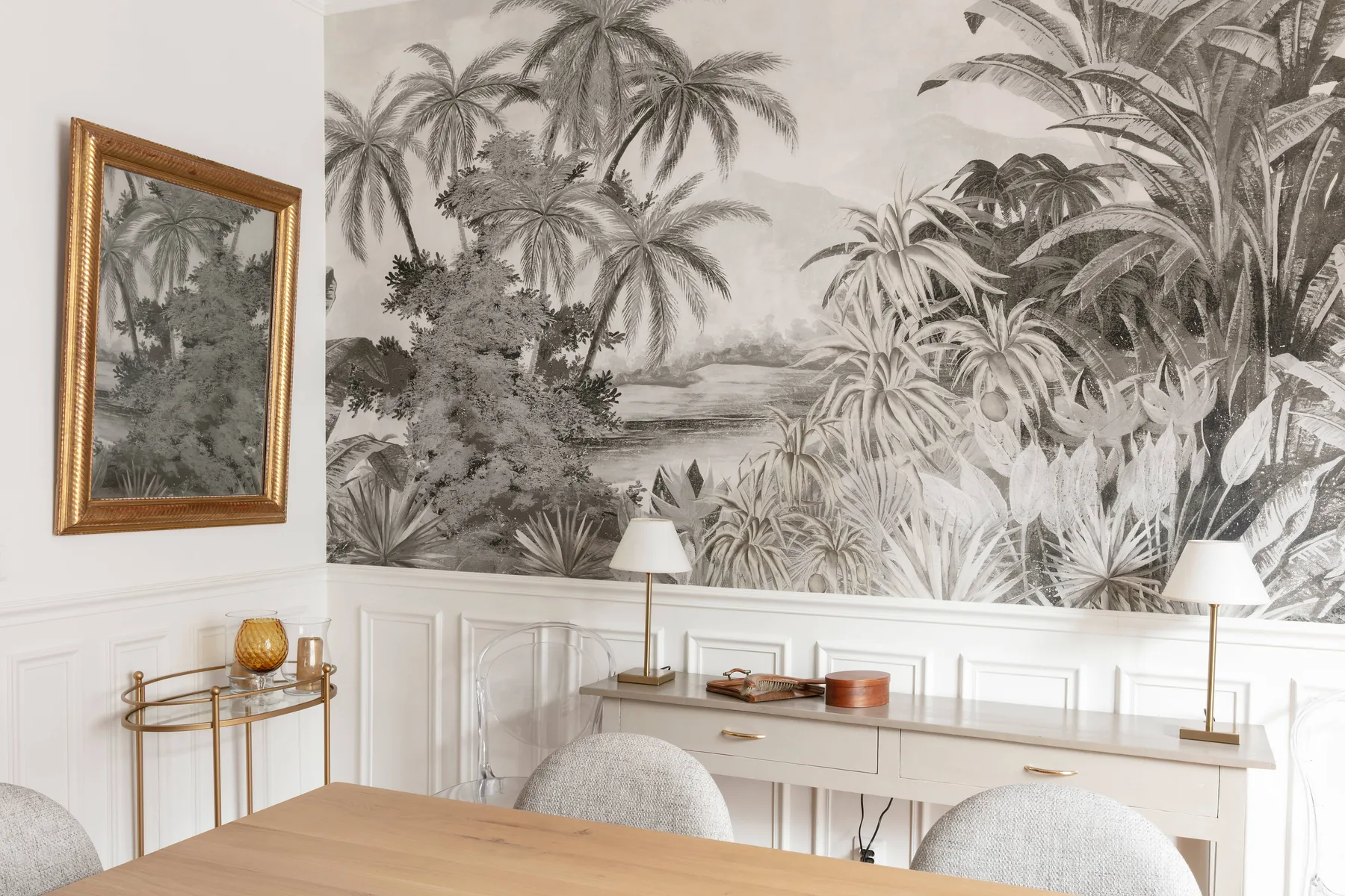 Un comedor con un mural botánico, una mesa de madera y asientos blancos.