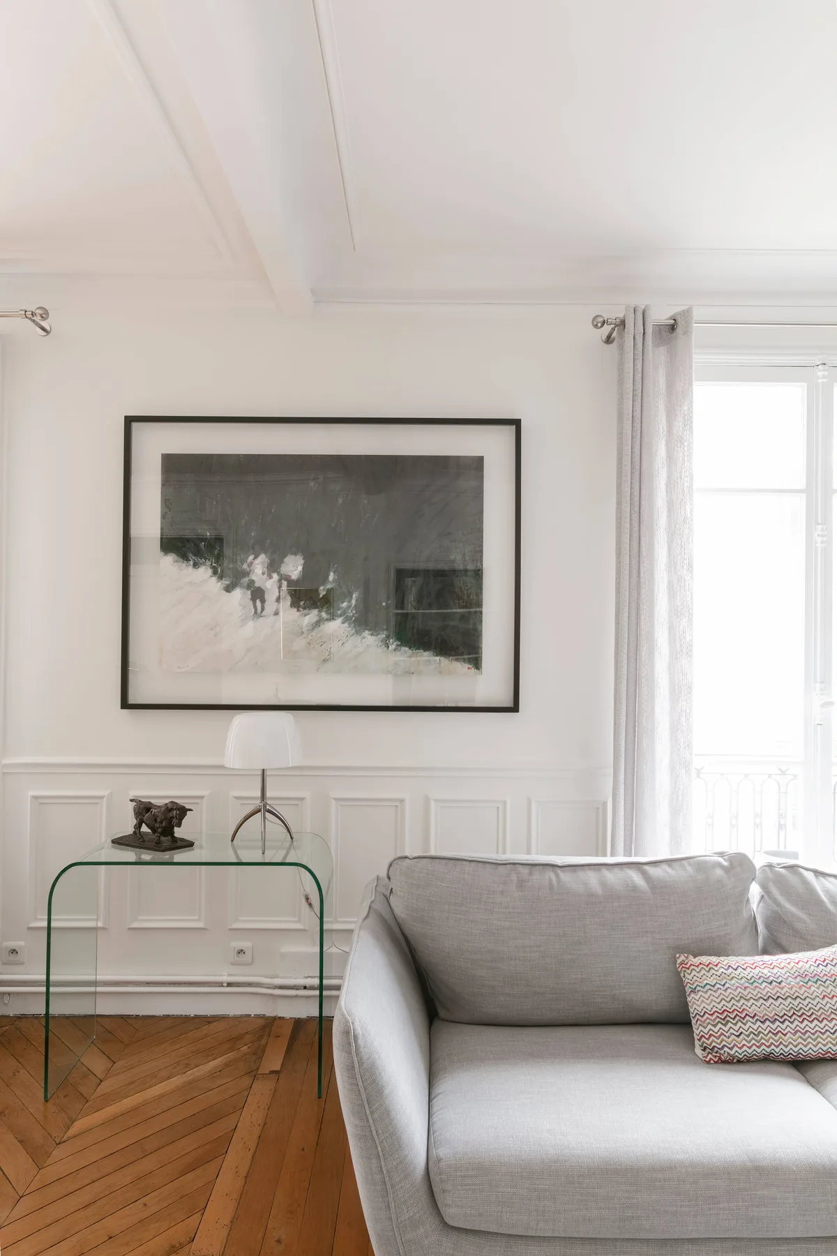 Una sala luminosa con asientos junto a una ventana grande y una obra enmarcada.