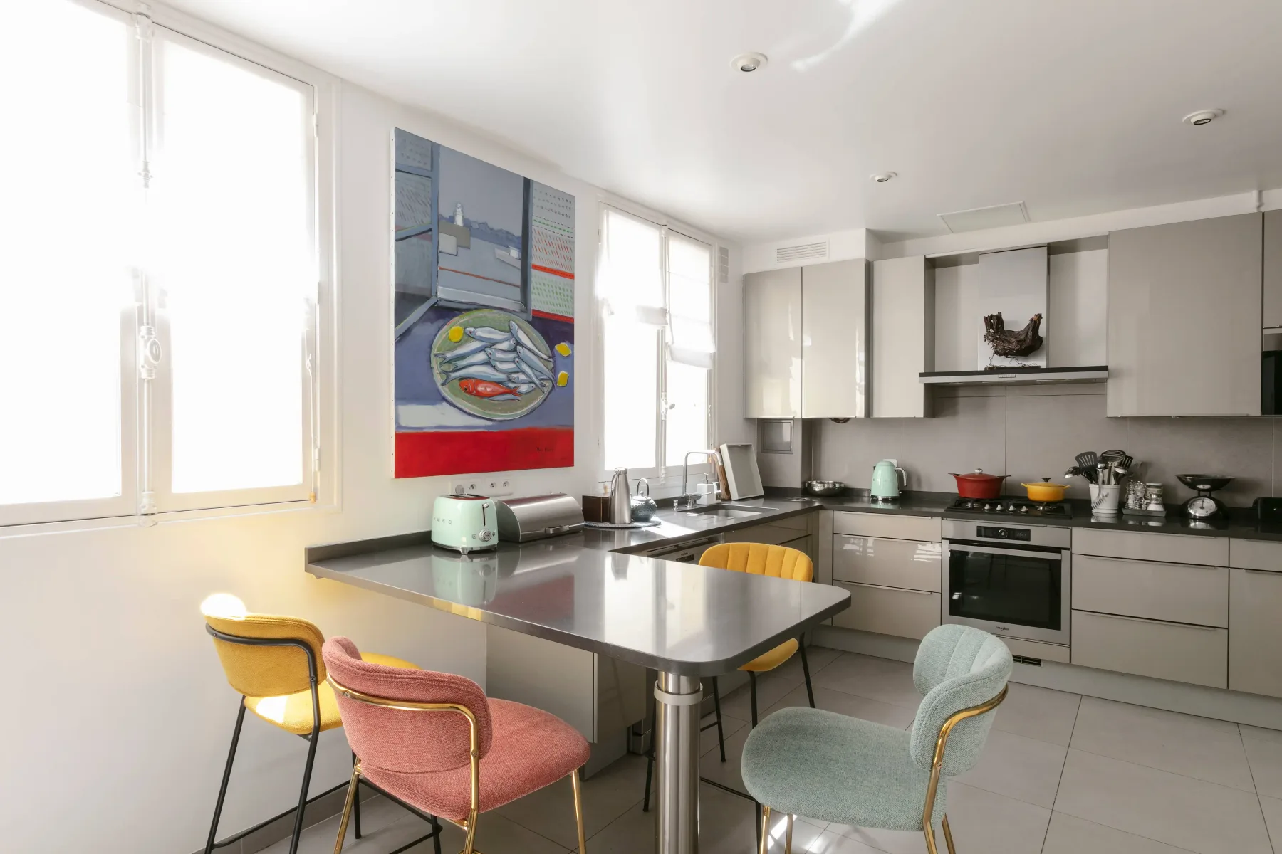 Una cocina moderna y luminosa con una isla central y asientos coloridos.