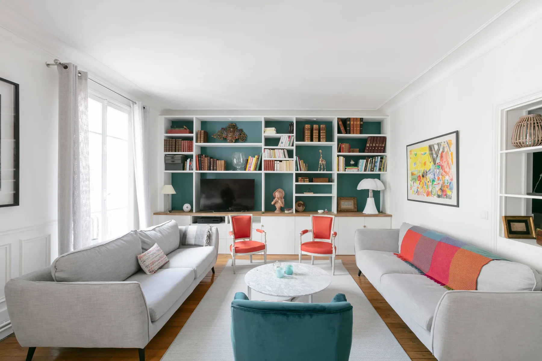 Una sala luminosa con asientos alrededor de una mesa de centro y estanterías empotradas.