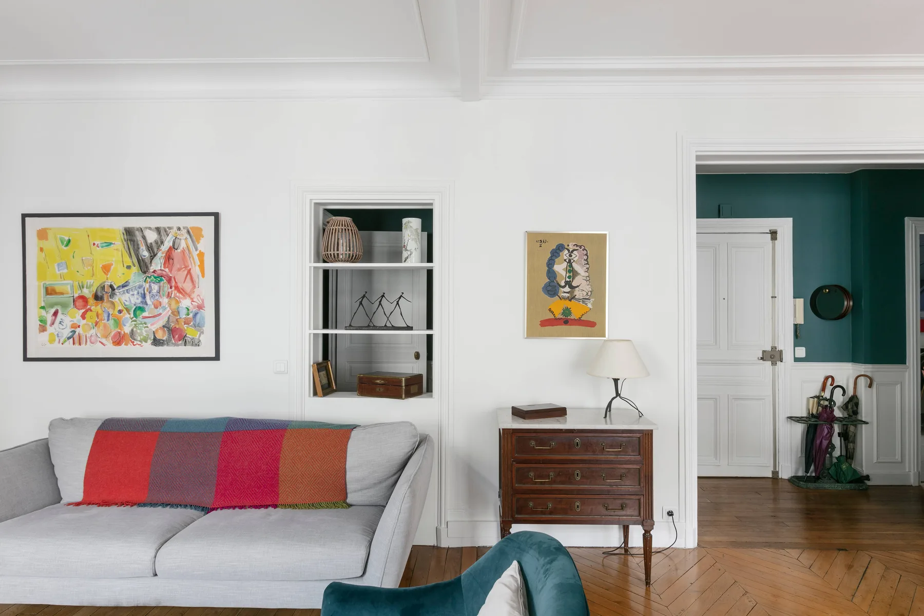Una sala de estar con asientos, cuadros enmarcados y un mueble de madera.
