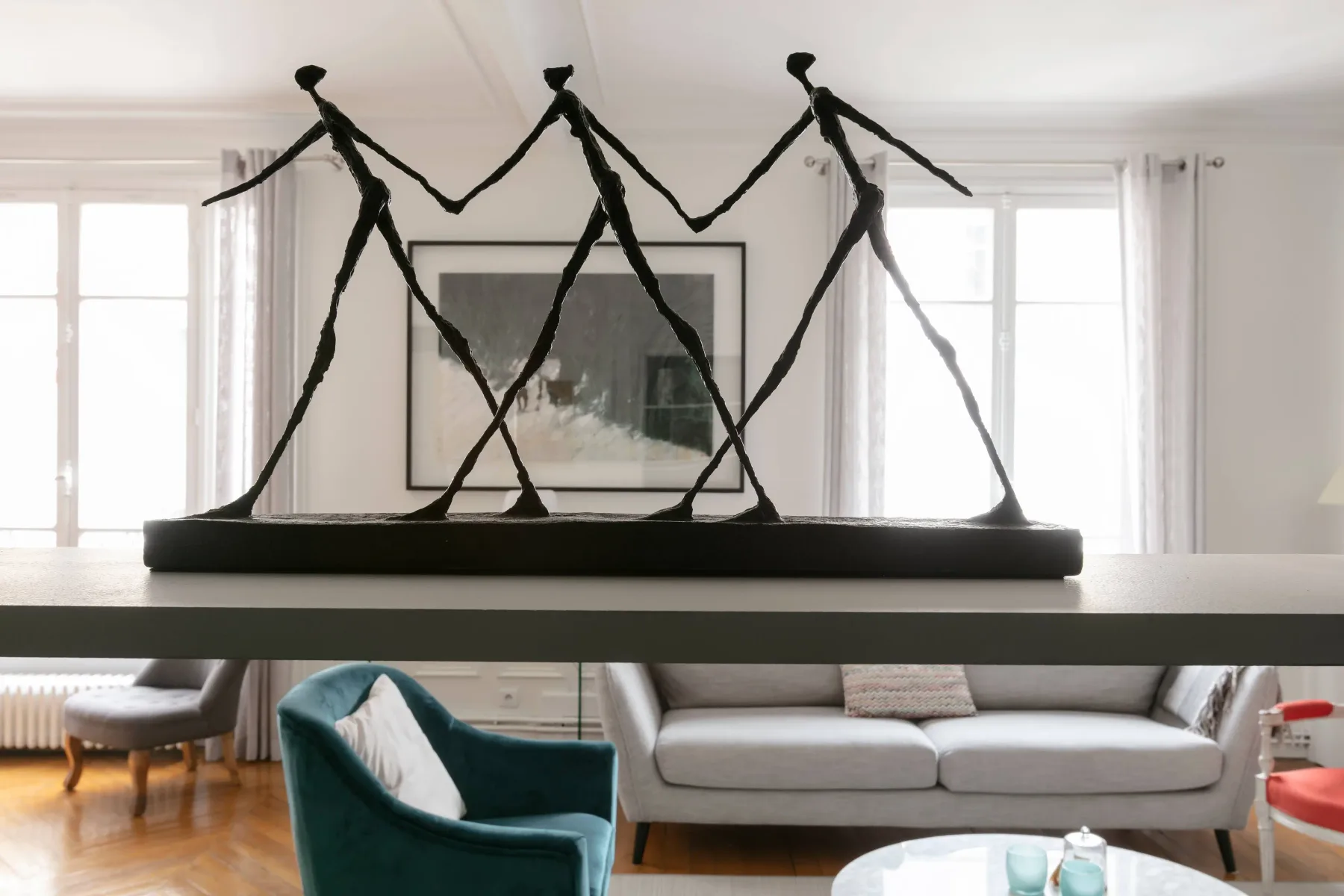 Una sala luminosa con un sofá y una gran escultura abstracta.