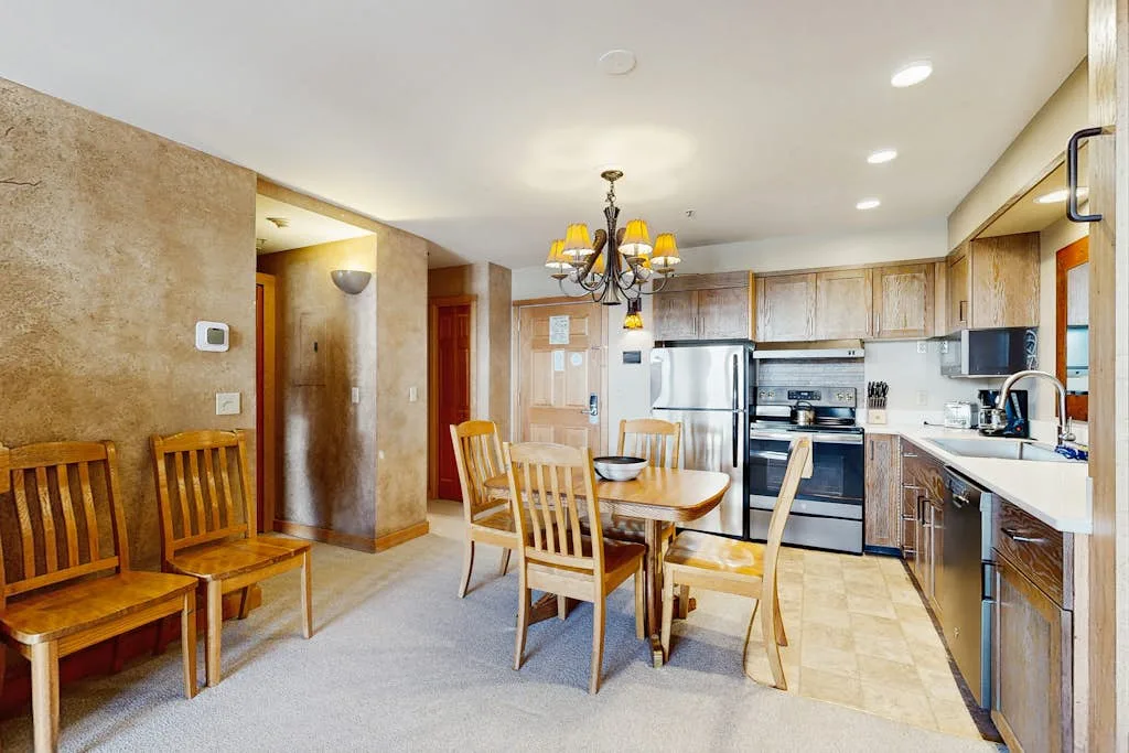 A dining area opens into a kitchen, with a wooden table and chairs.