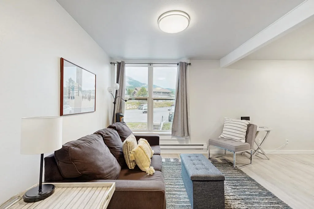 A bright living room with a sofa, coffee table, and large window.