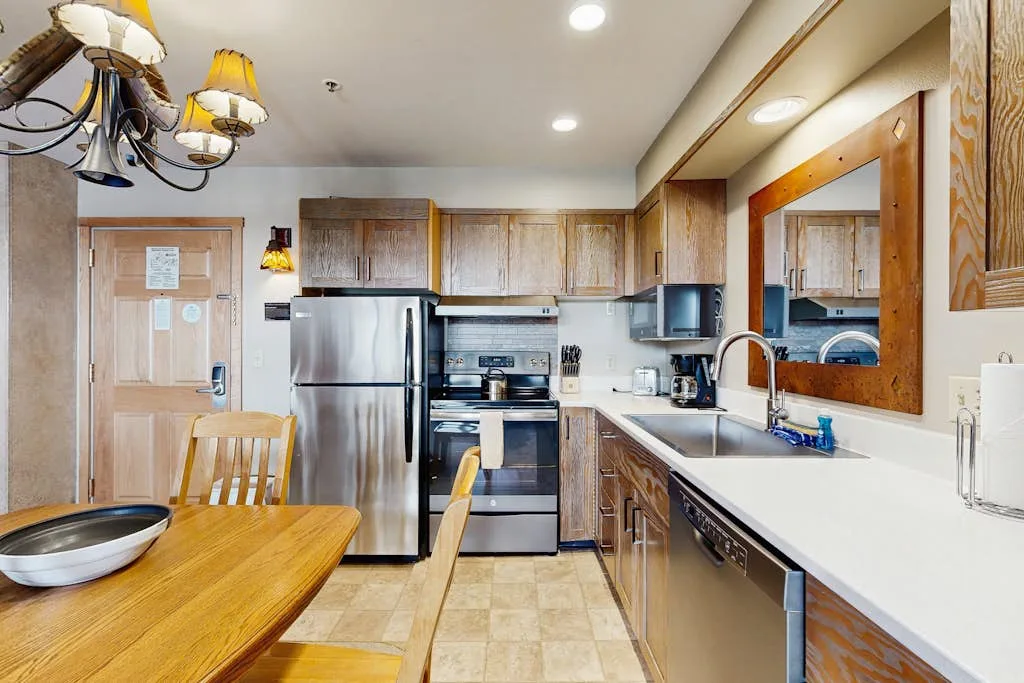 A kitchen with wooden cabinets, stainless steel appliances, and a dining table.