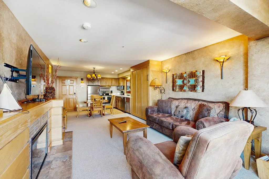 A living room with seating, a coffee table, and an open kitchen in the background.