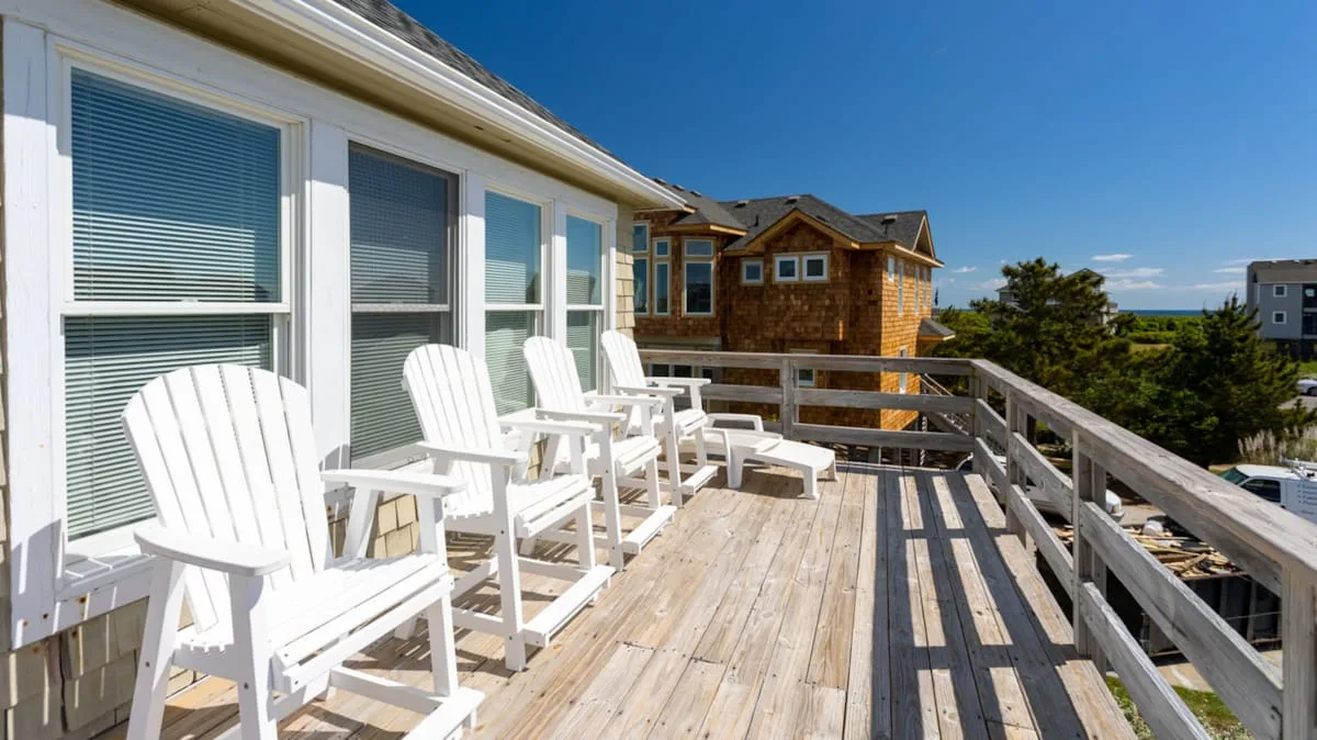 Una terraza de madera con asientos blancos junto a una casa.