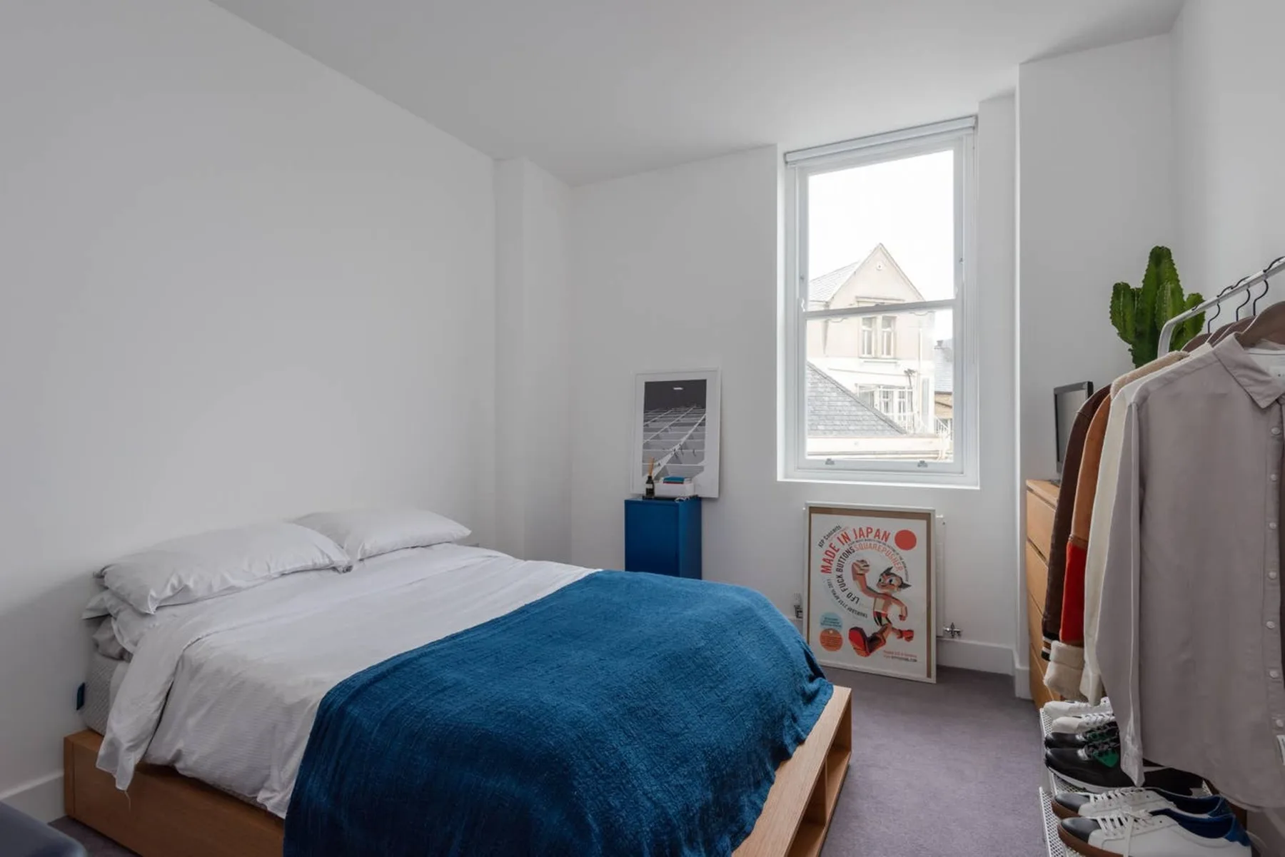 Un dormitorio con una cama cubierta por una manta azul y una ventana.