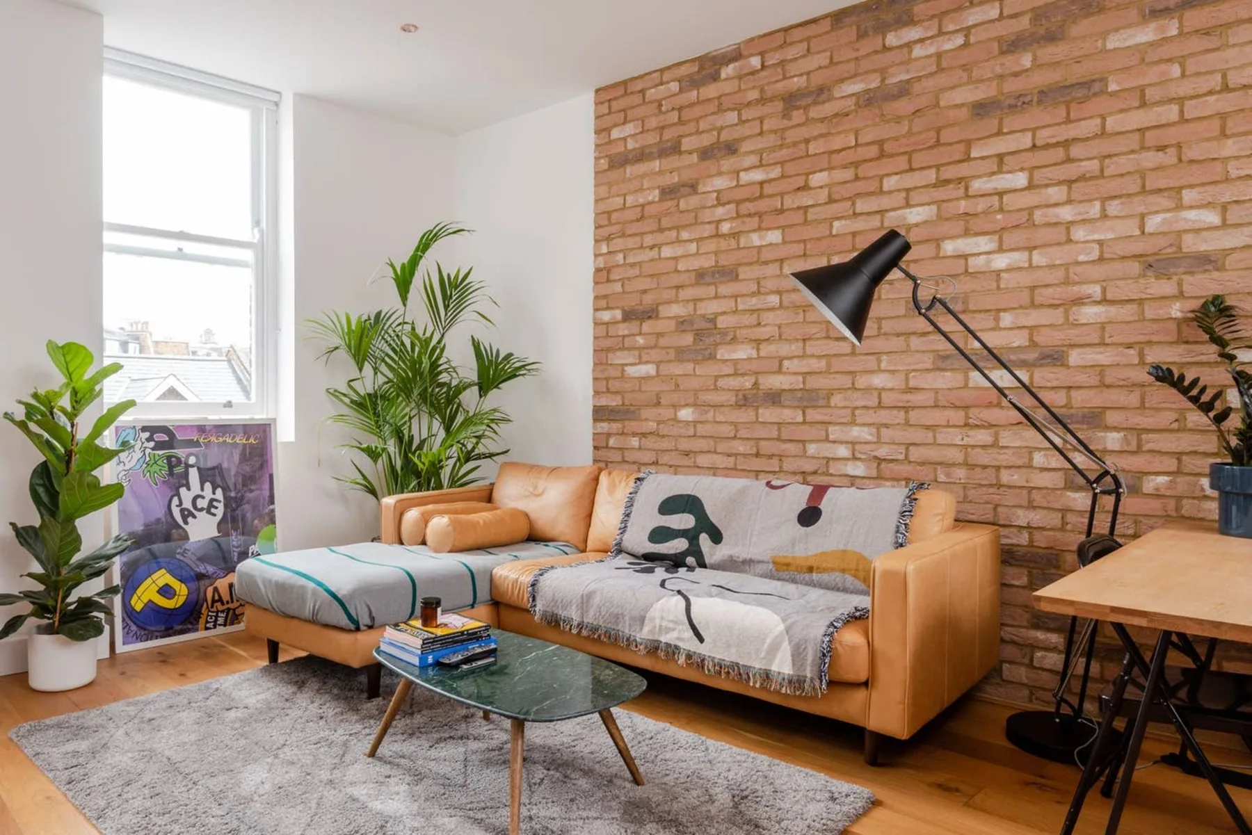 A living room with seating, a brick wall, and a tall floor lamp.