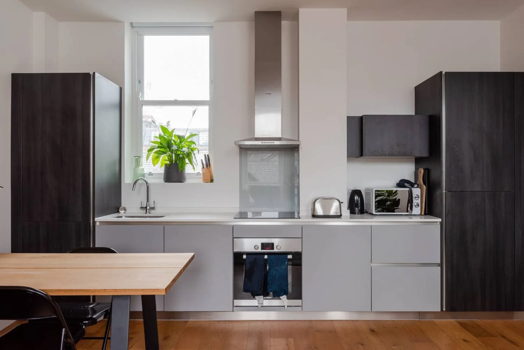 Una cocina moderna con gabinetes oscuros, una cocina y una mesa de comedor.