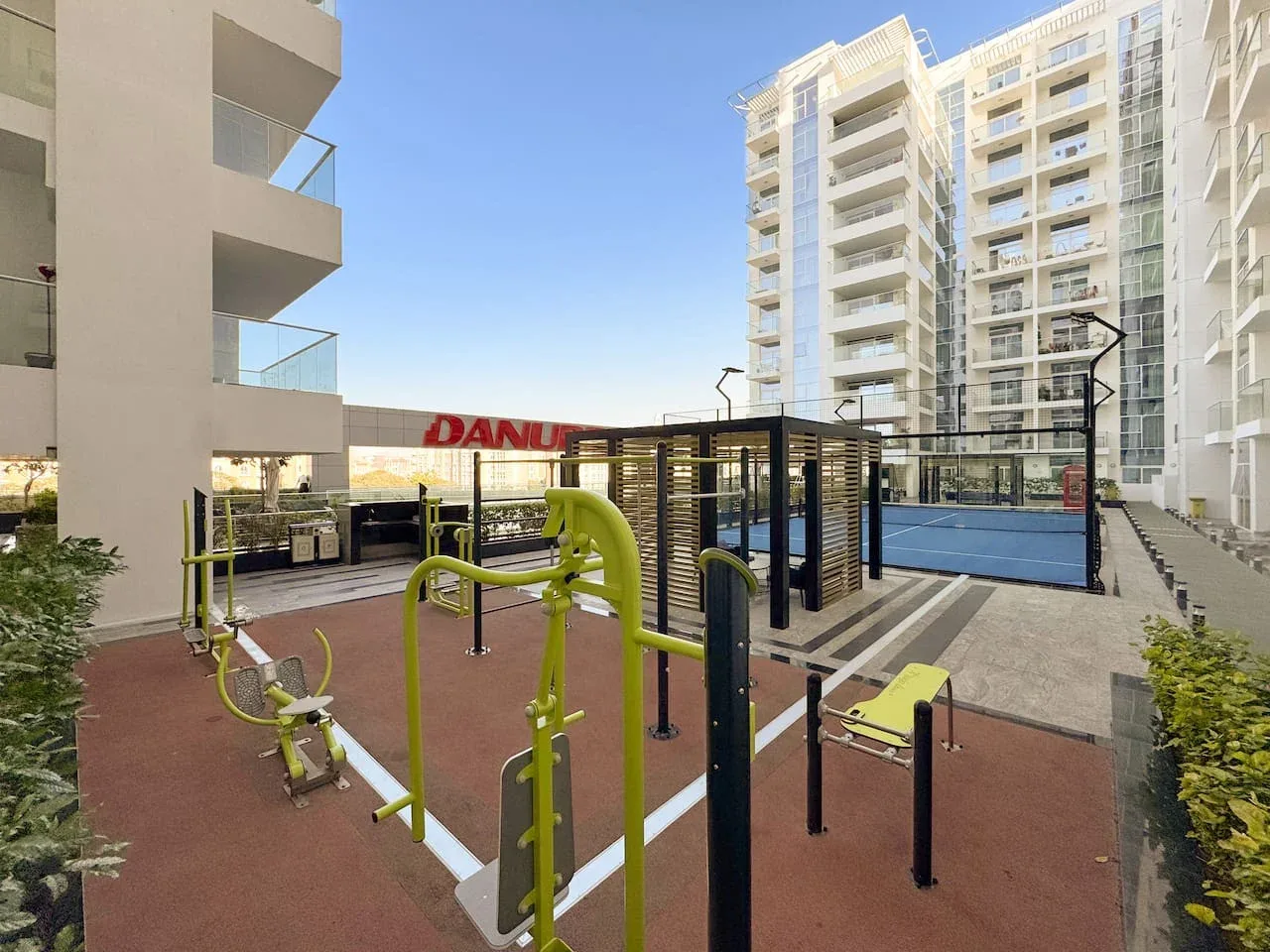 Una zona de ejercicio al aire libre con equipos está entre edificios de apartamentos modernos.