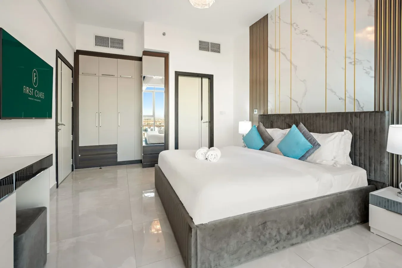 Un dormitorio con una cama grande, ropa de cama blanca y cojines azules.