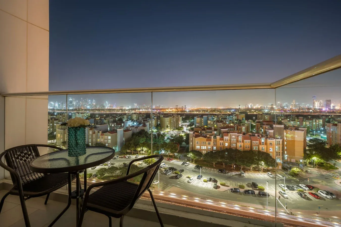 Una zona de estar en el balcón ofrece vistas de la ciudad iluminada por la noche.