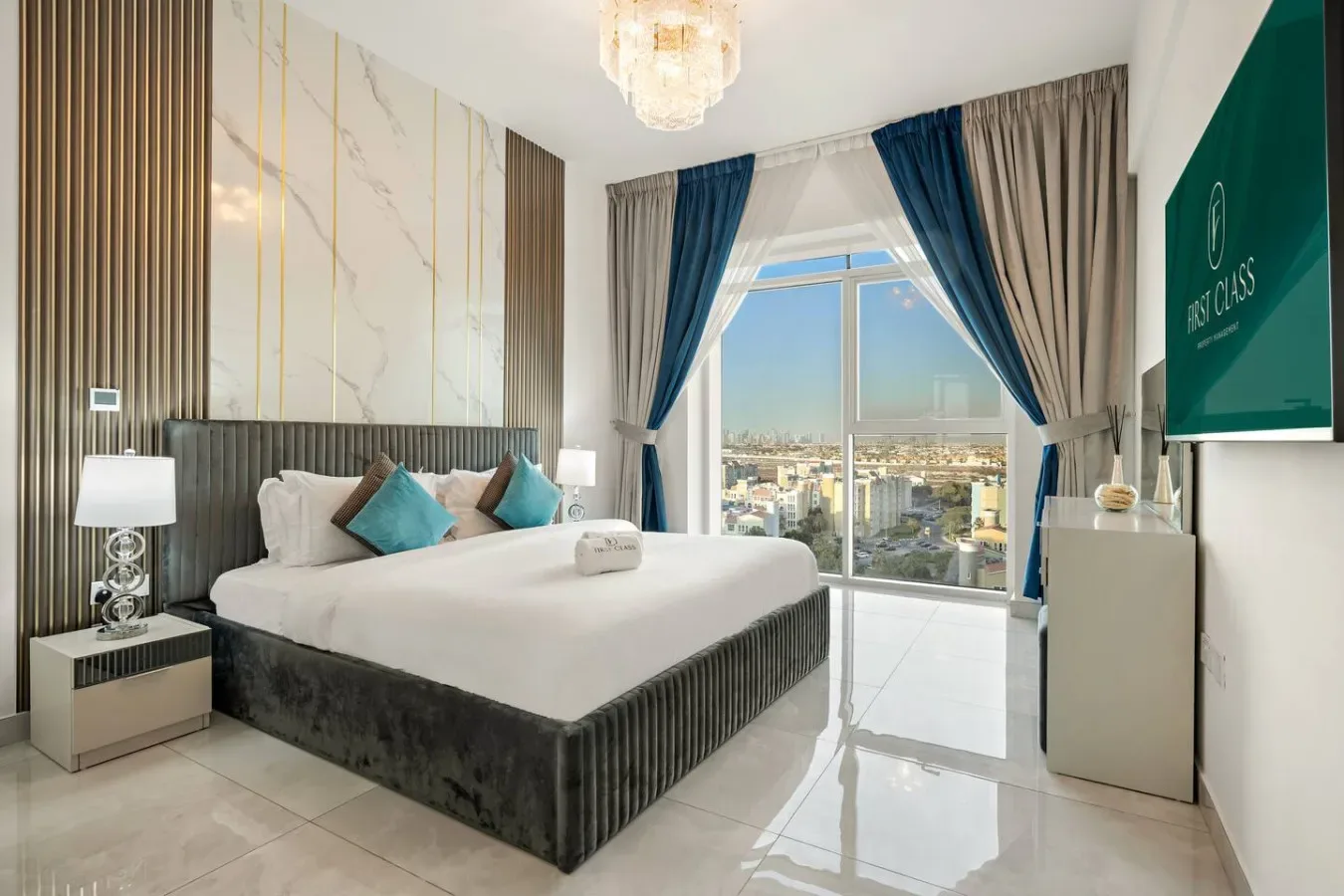 Un dormitorio luminoso cuenta con una cama grande junto a ventanales con vistas a la ciudad.