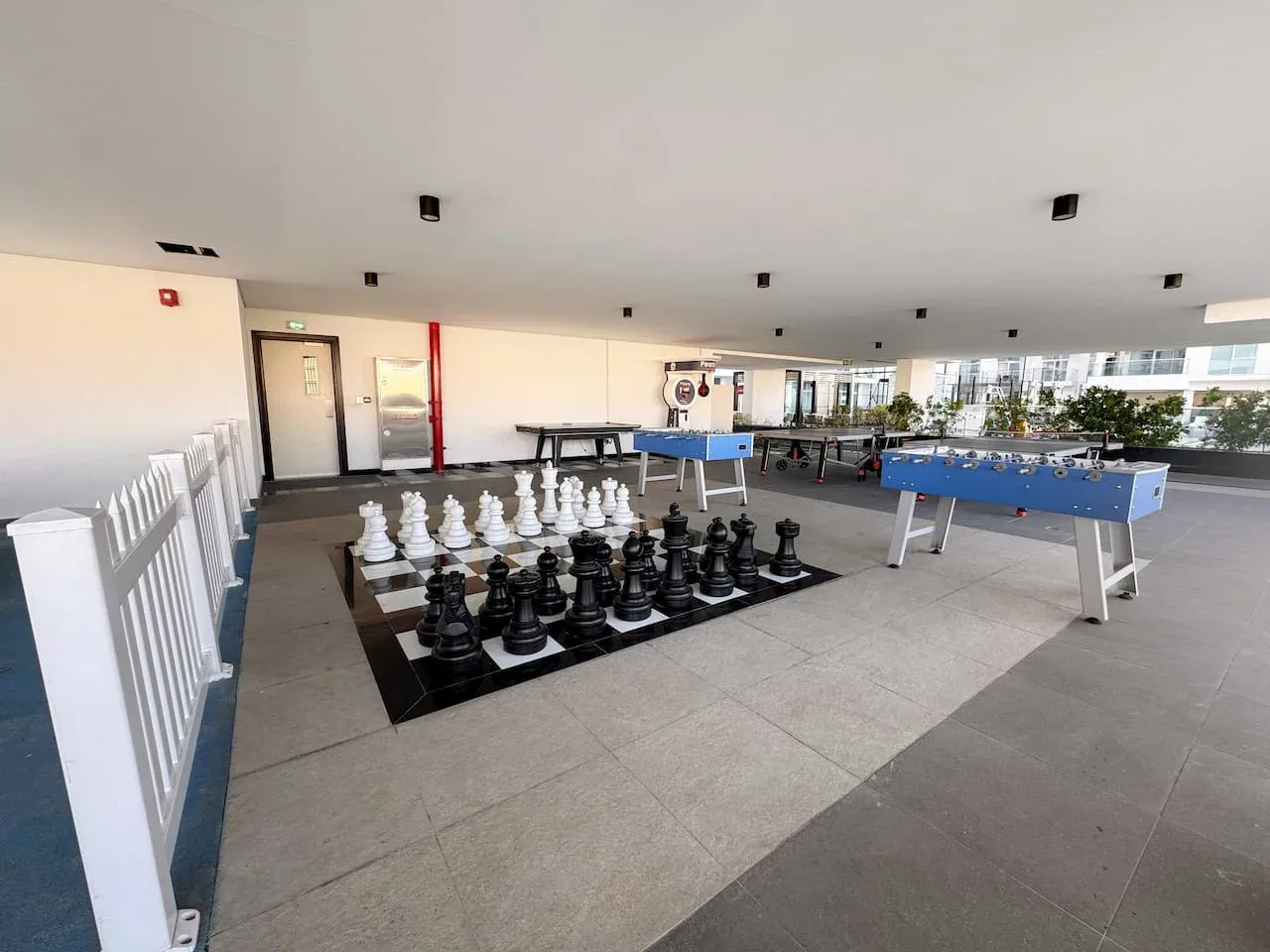 Una zona recreativa cubierta con un tablero de ajedrez grande y futbolines.