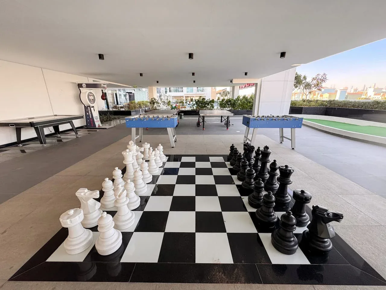 Un tablero de ajedrez gigante con piezas blancas y negras está bajo una zona recreativa cubierta.