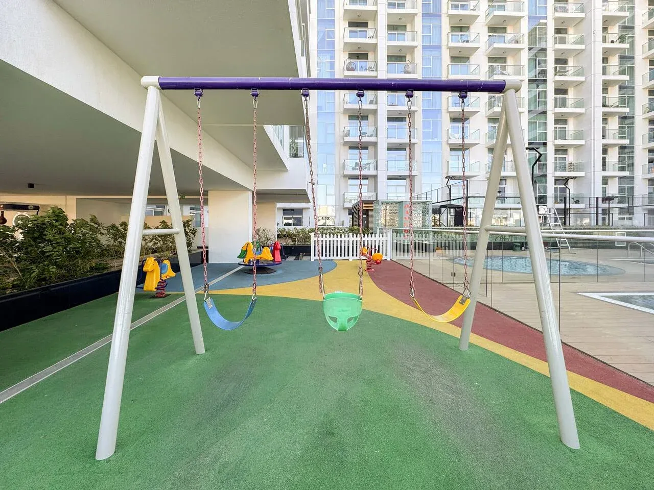 Un columpio está sobre una colorida superficie de juegos al aire libre.