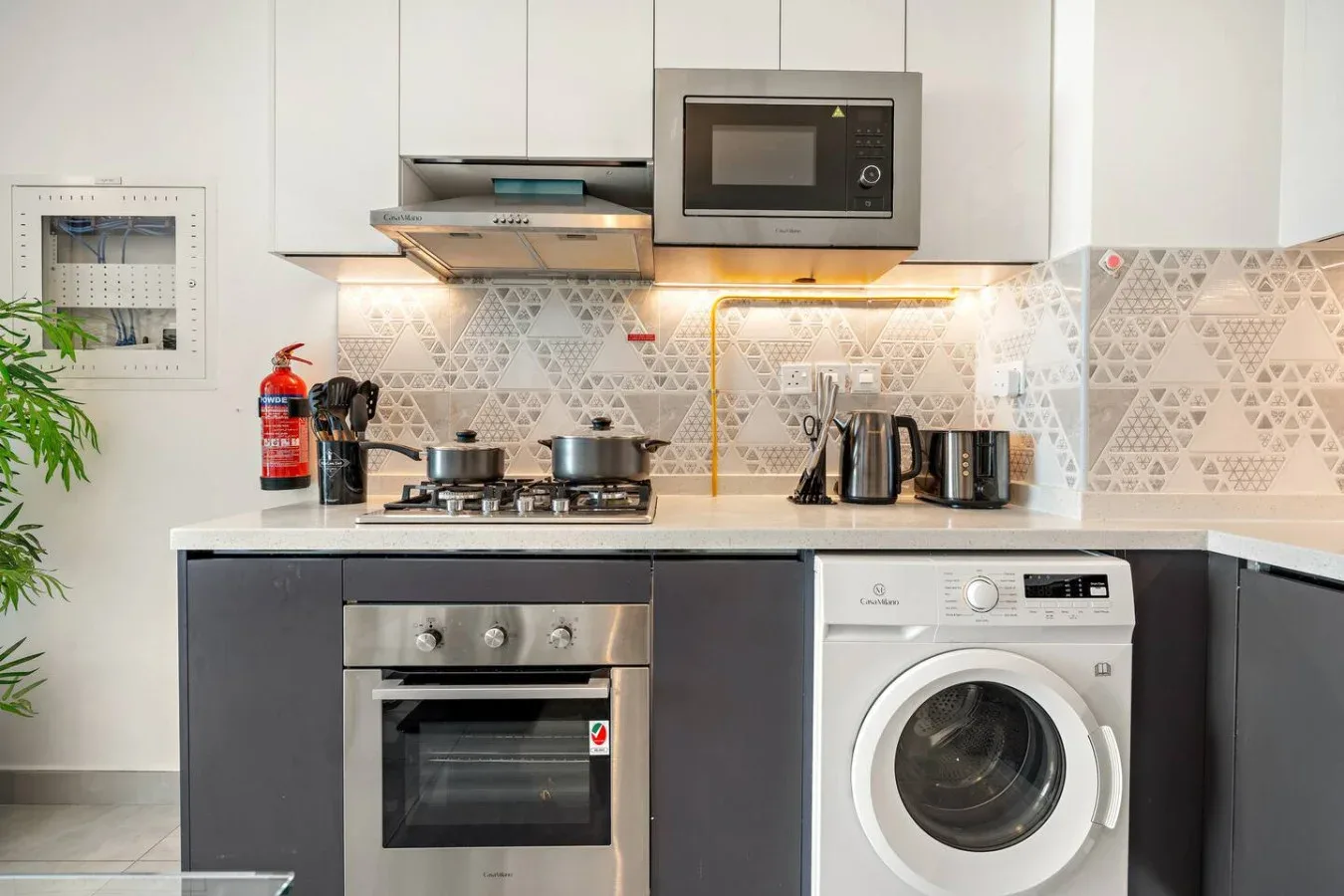 Una cocina compacta con placa, horno, microondas y lavadora.