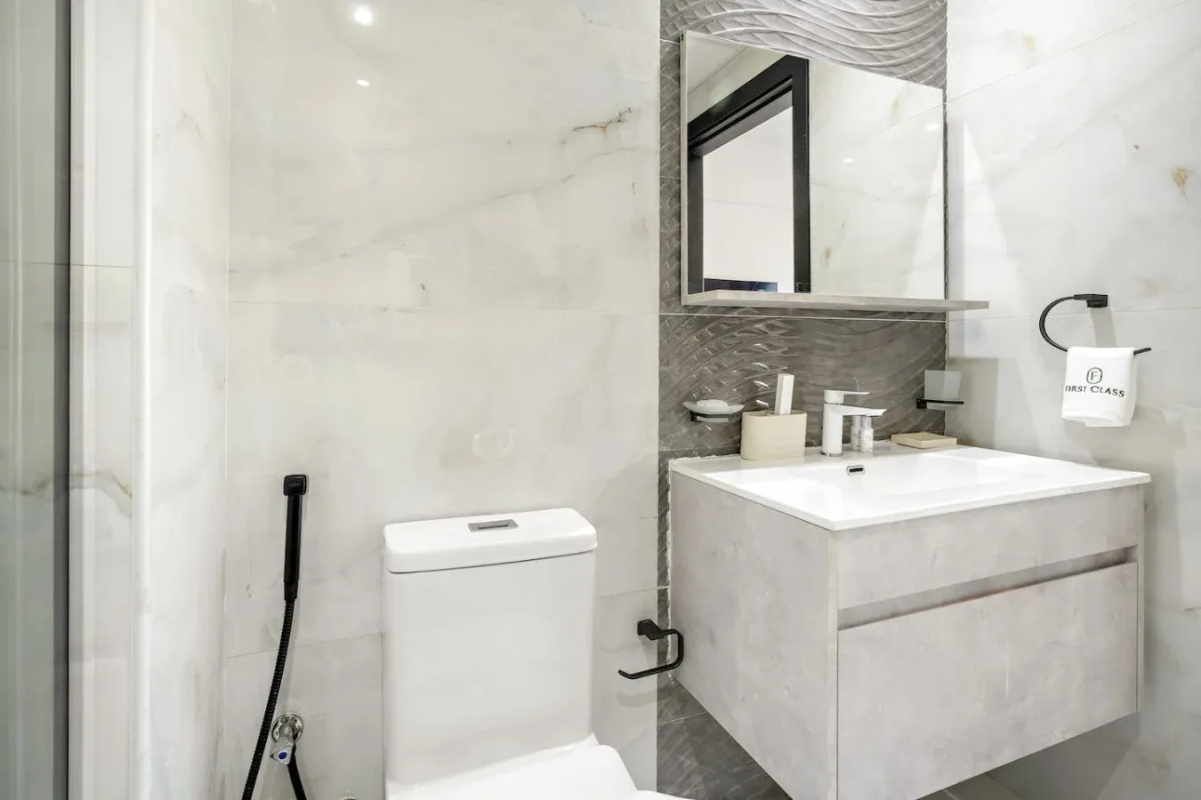 Baño revestido de mármol con inodoro y lavabo suspendido.