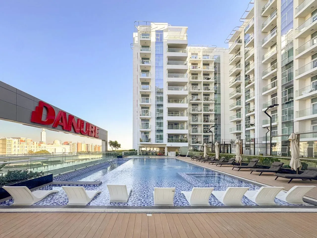 Una piscina al aire libre está junto a edificios modernos de gran altura.