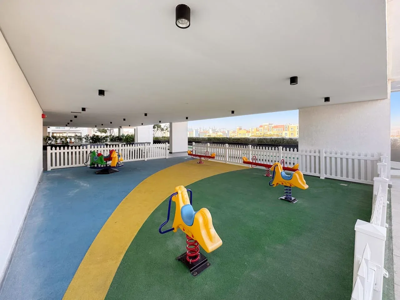 Una zona de juegos cubierta con juegos de resorte coloridos sobre un suelo pintado.