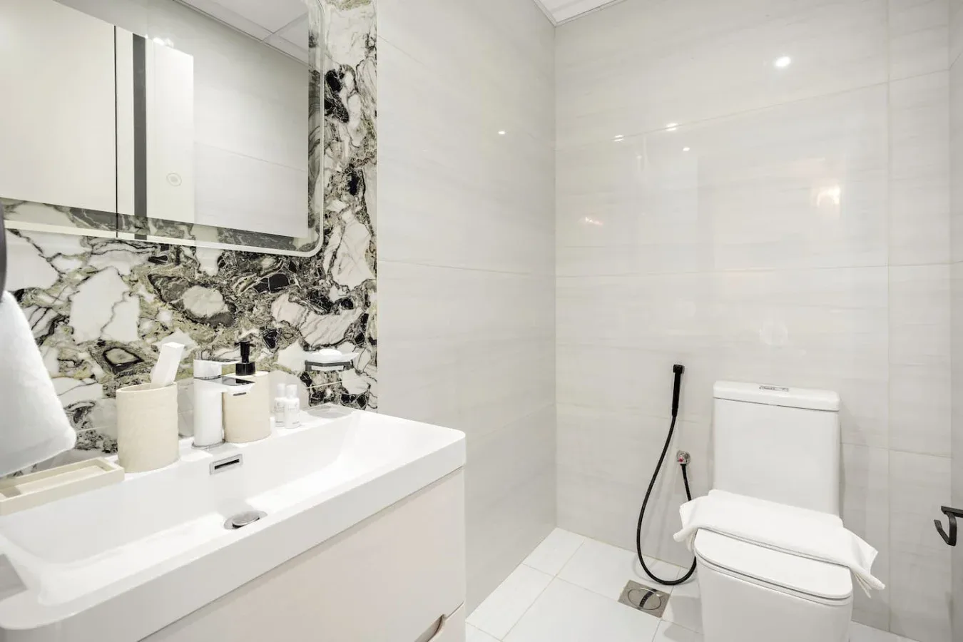 Un baño luminoso con azulejos, un lavabo amplio y un inodoro.