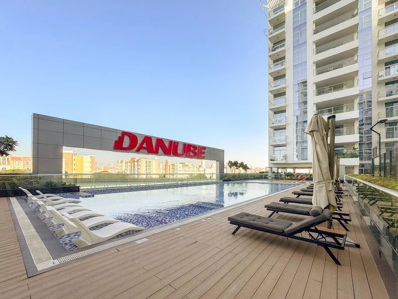 Una piscina en la azotea junto a un edificio alto, con asientos en la terraza.