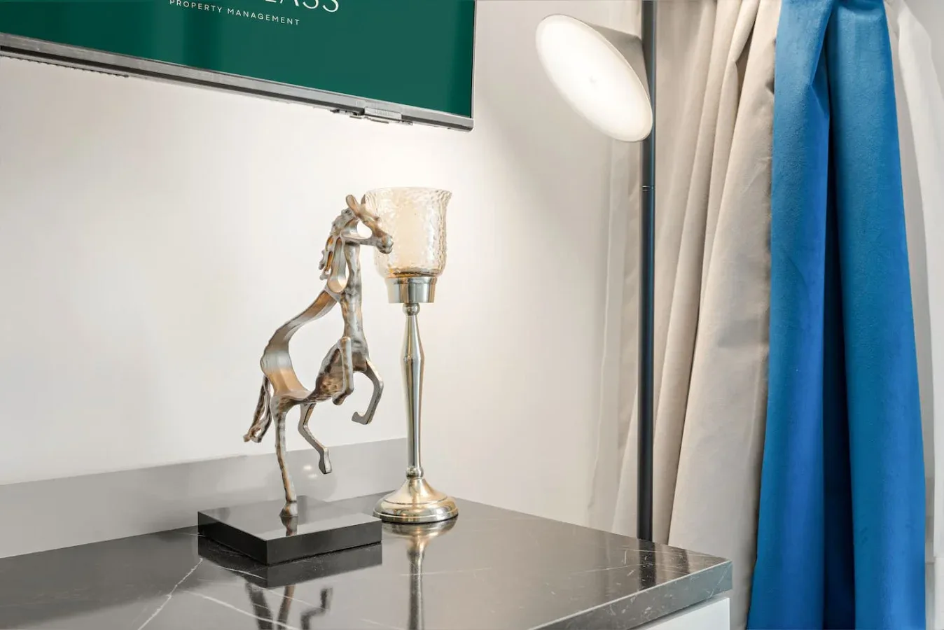 Una mesa metálica sostiene una figura decorativa de caballo junto a una lámpara.