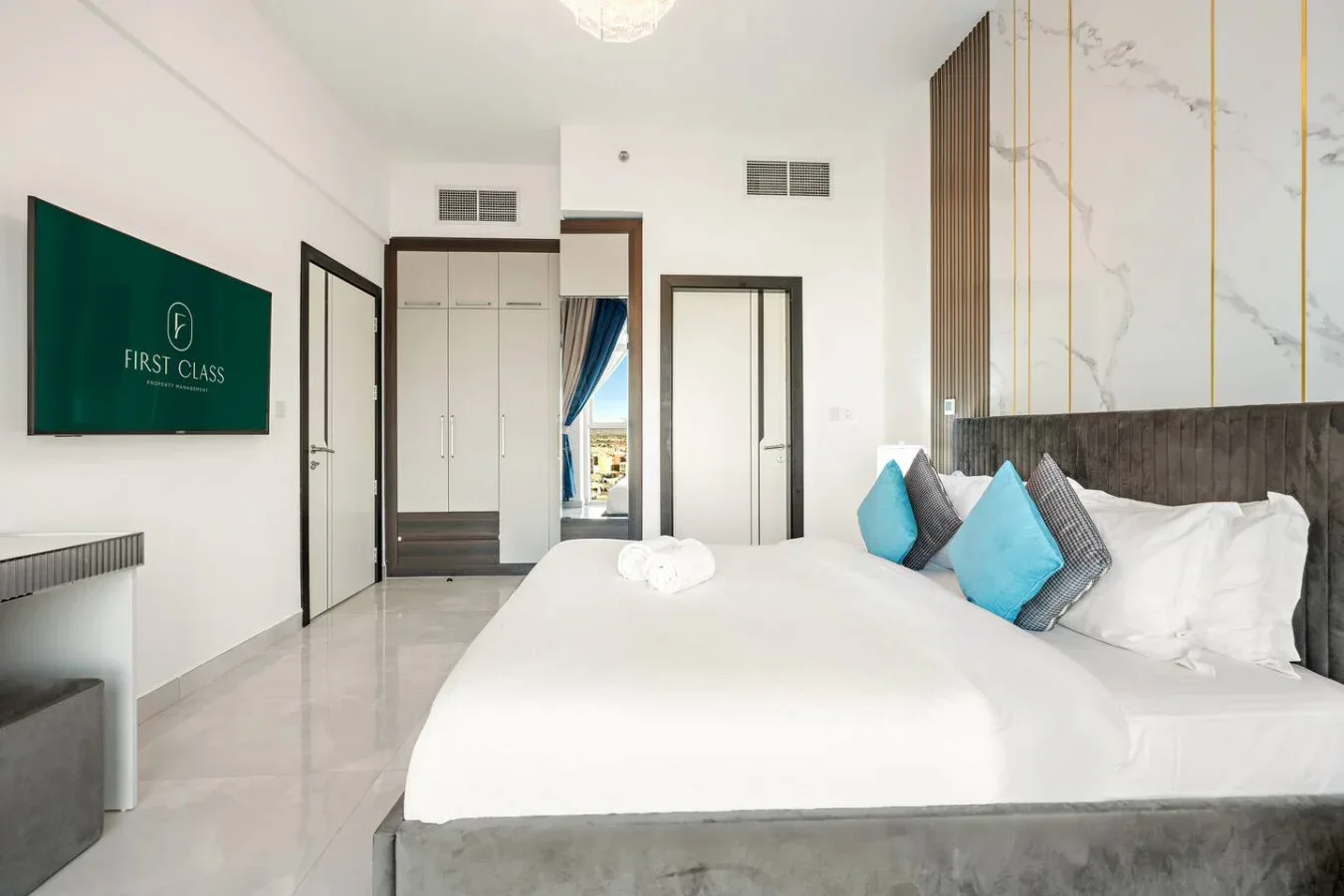 Un dormitorio luminoso con una cama grande y un televisor en la pared.