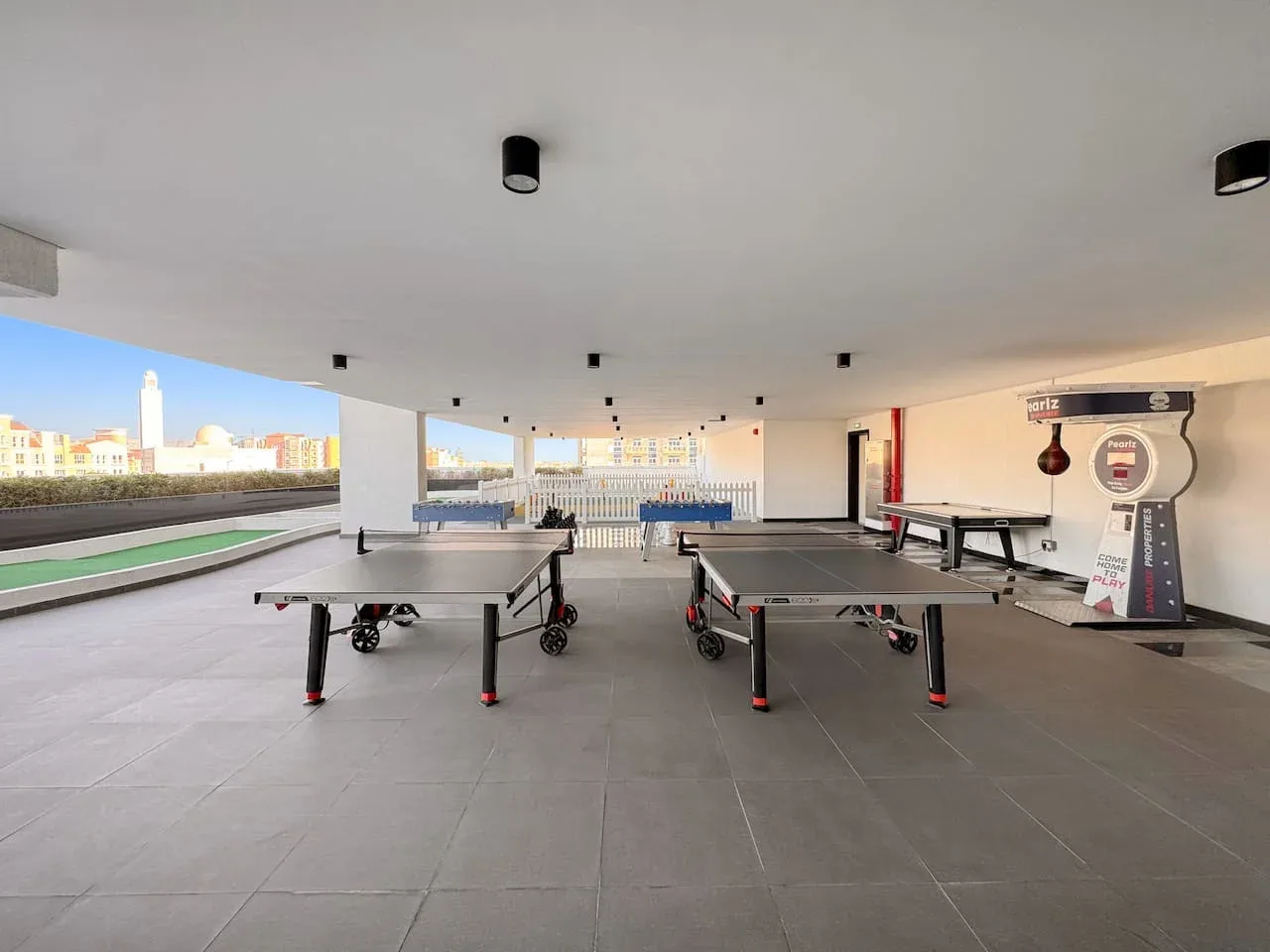 Una zona recreativa cubierta con mesas de ping-pong y laterales abiertos.