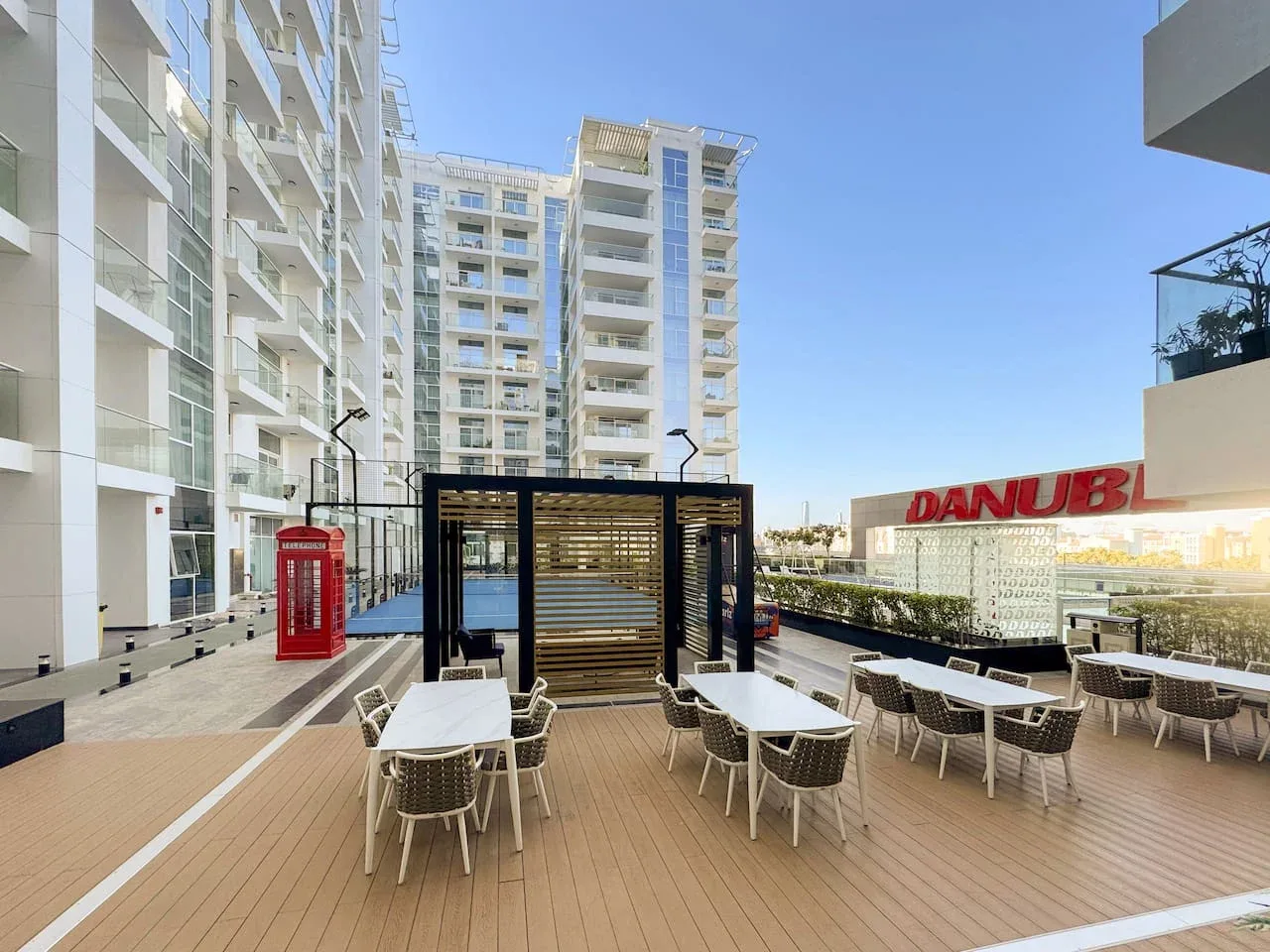 Una terraza exterior con mesas y asientos junto a modernos edificios altos.