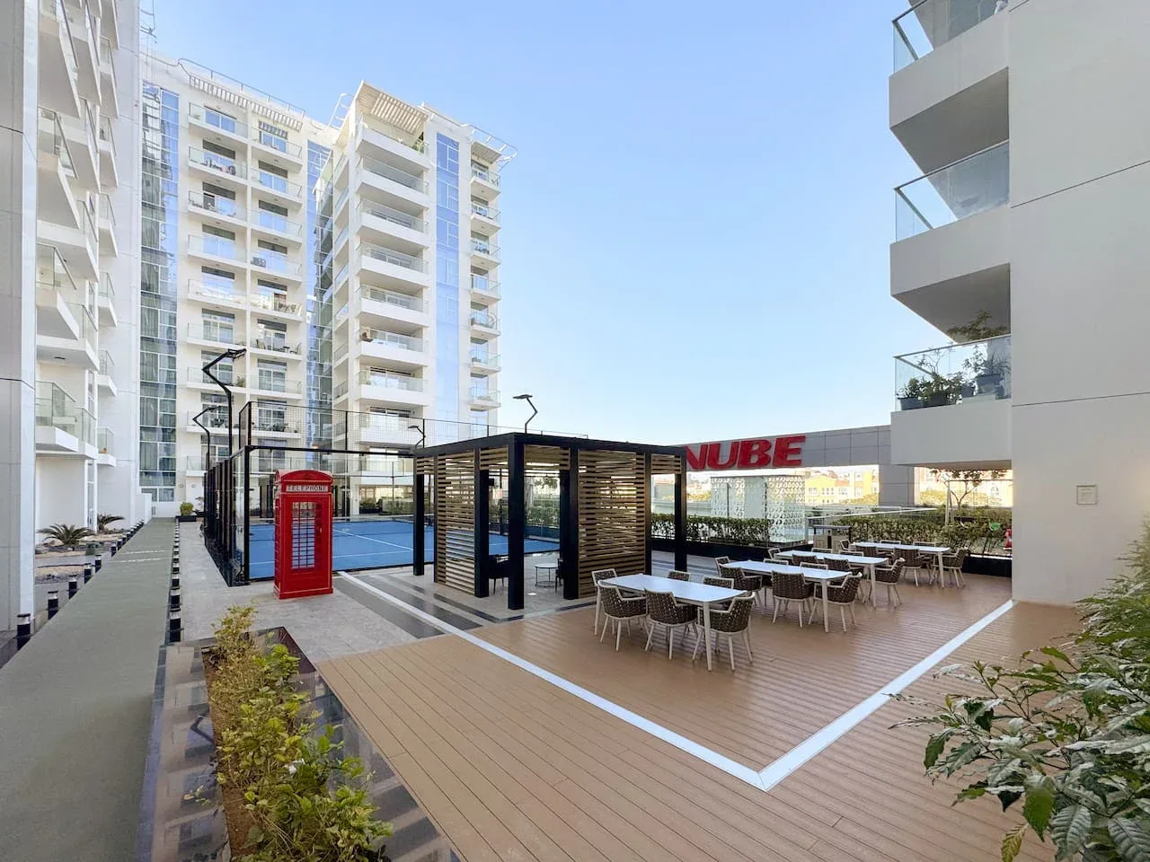Una terraza al aire libre con mesas y asientos junto a un edificio moderno.