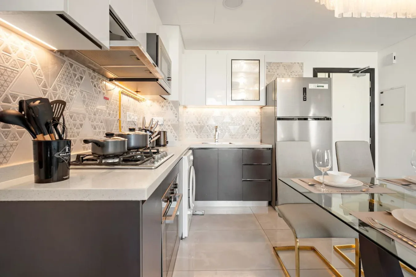 Una cocina moderna con gabinetes oscuros, electrodomésticos de acero inoxidable y una mesa de comedor.