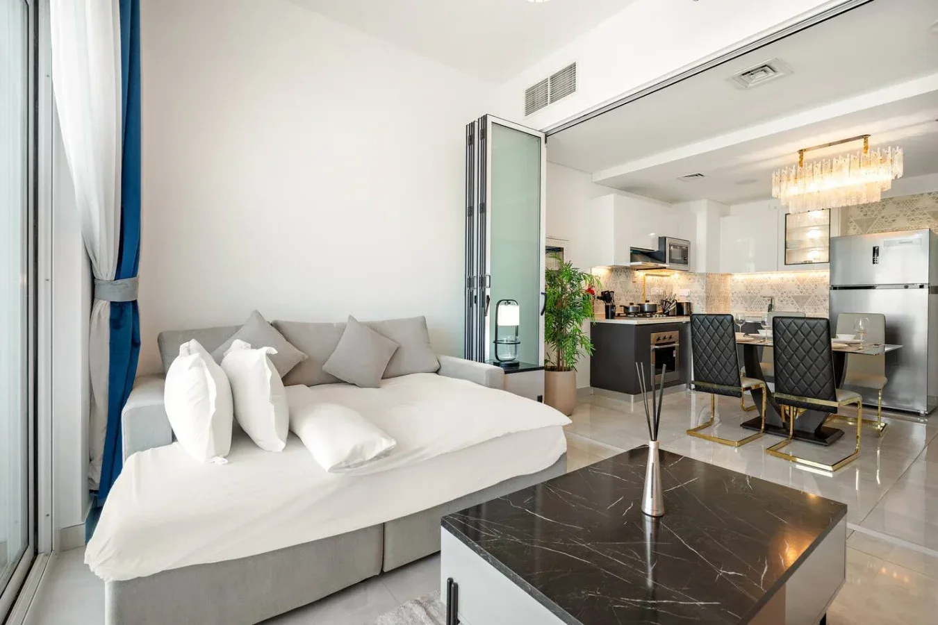 Una luminosa zona diáfana de estar y comedor con cama, asientos y cocina.