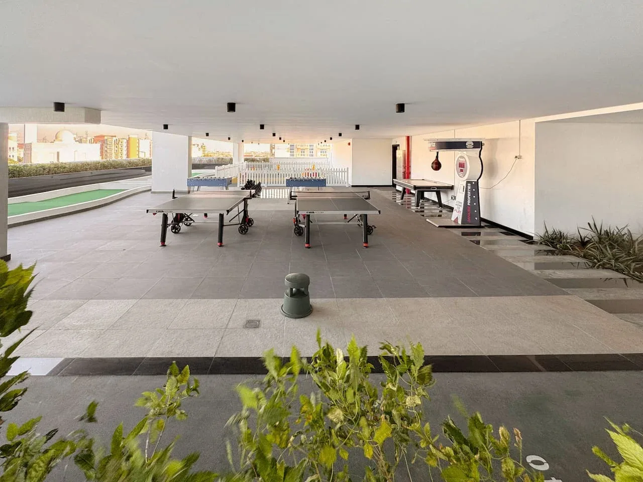 Zona recreativa abierta con mesas de ping-pong y una mesa de futbolín.