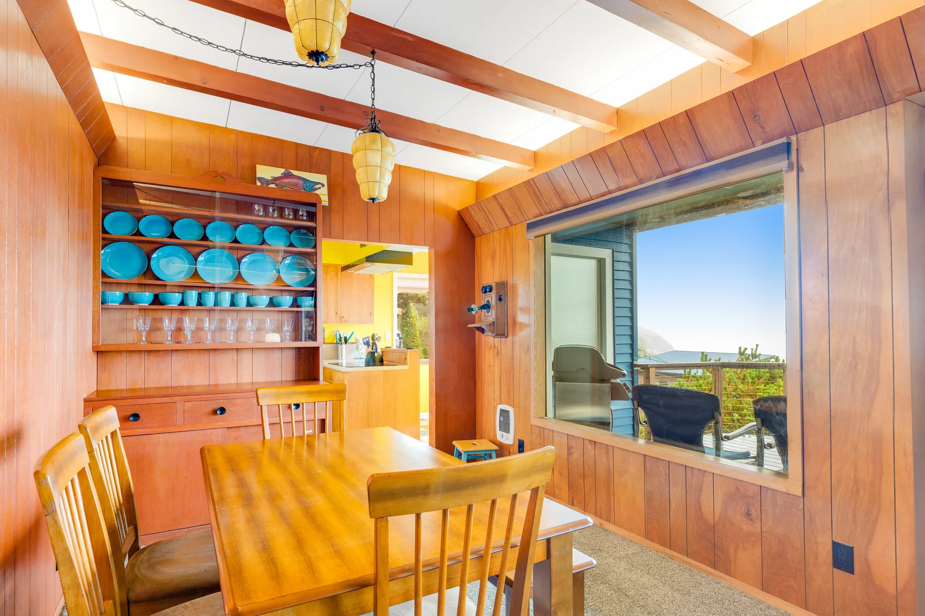 A wood-paneled dining area with a table and a large window overlooking the outdoors.