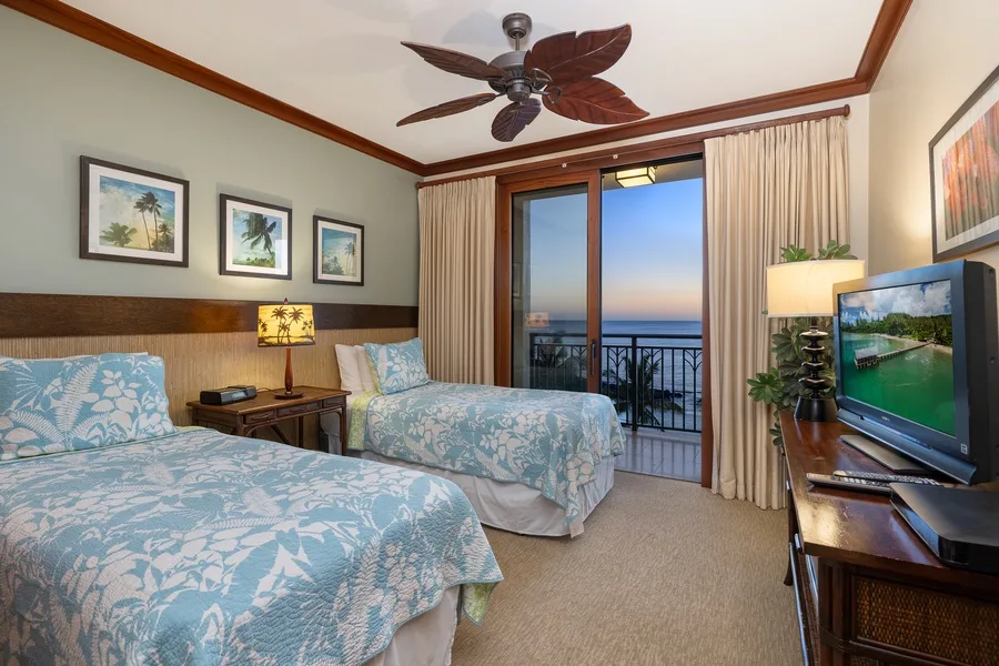 A bedroom with two beds, a television, and an open balcony doorway.